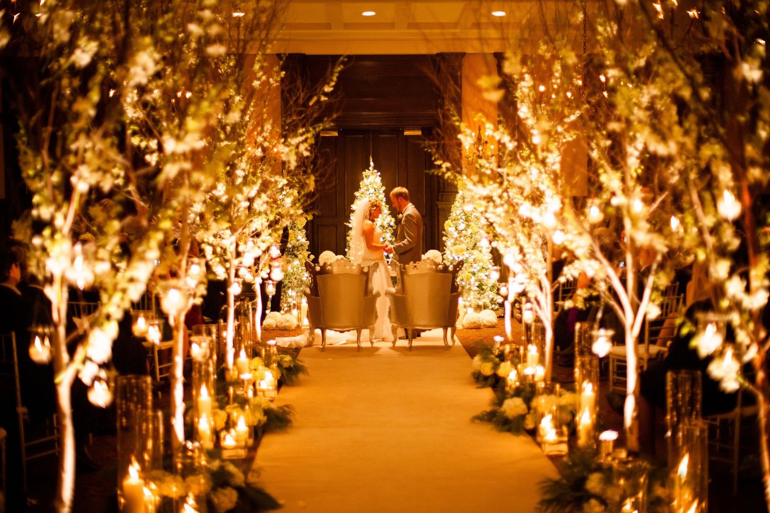 Elegant wedding reception hall featuring a walkway lined with illuminated blossom trees