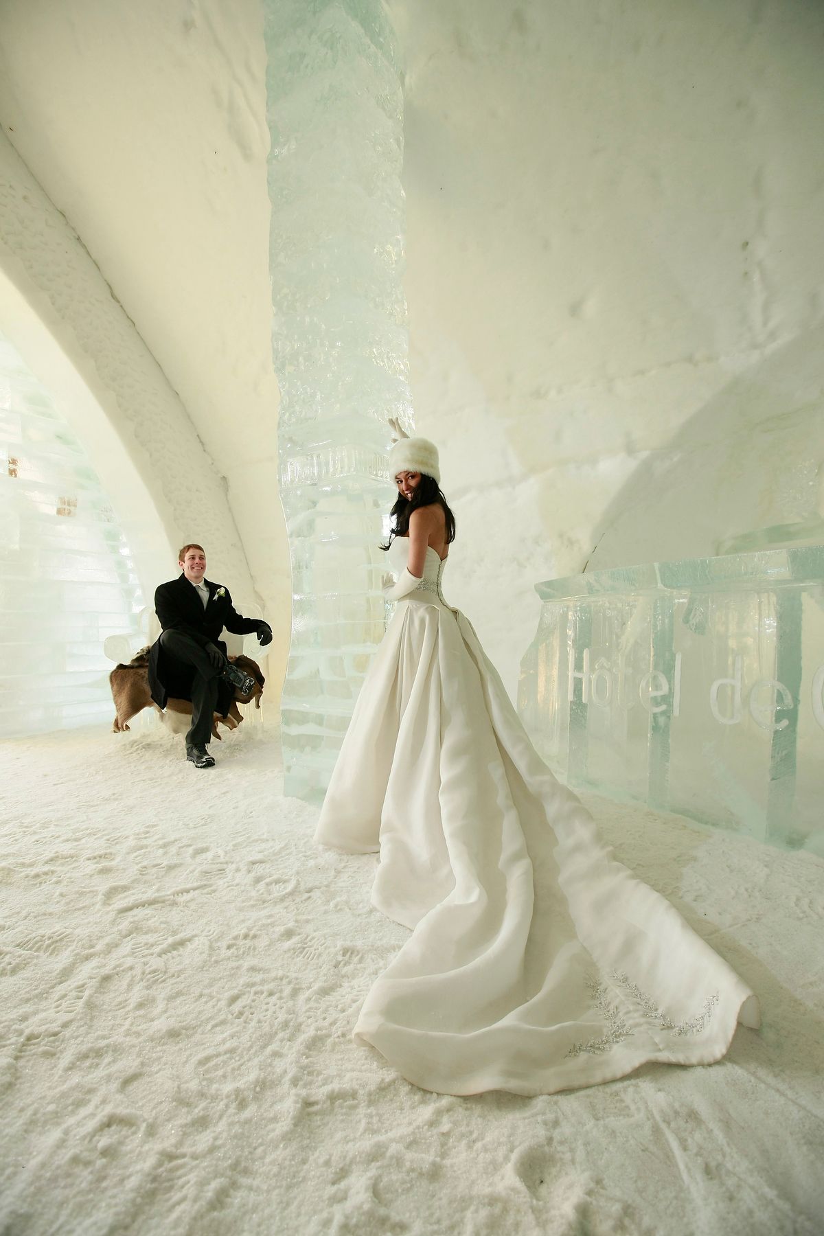 Wide perspective portrait of a bride with a dramatic gown train in the Ice Hotel, Quebec