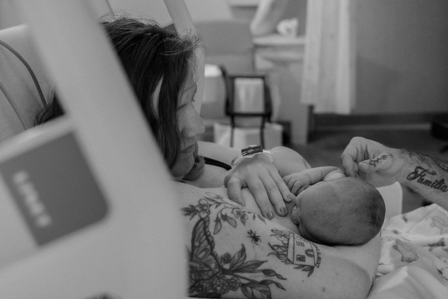 Mother gazing lovingly at her newborn baby in a hospital room after giving birth.