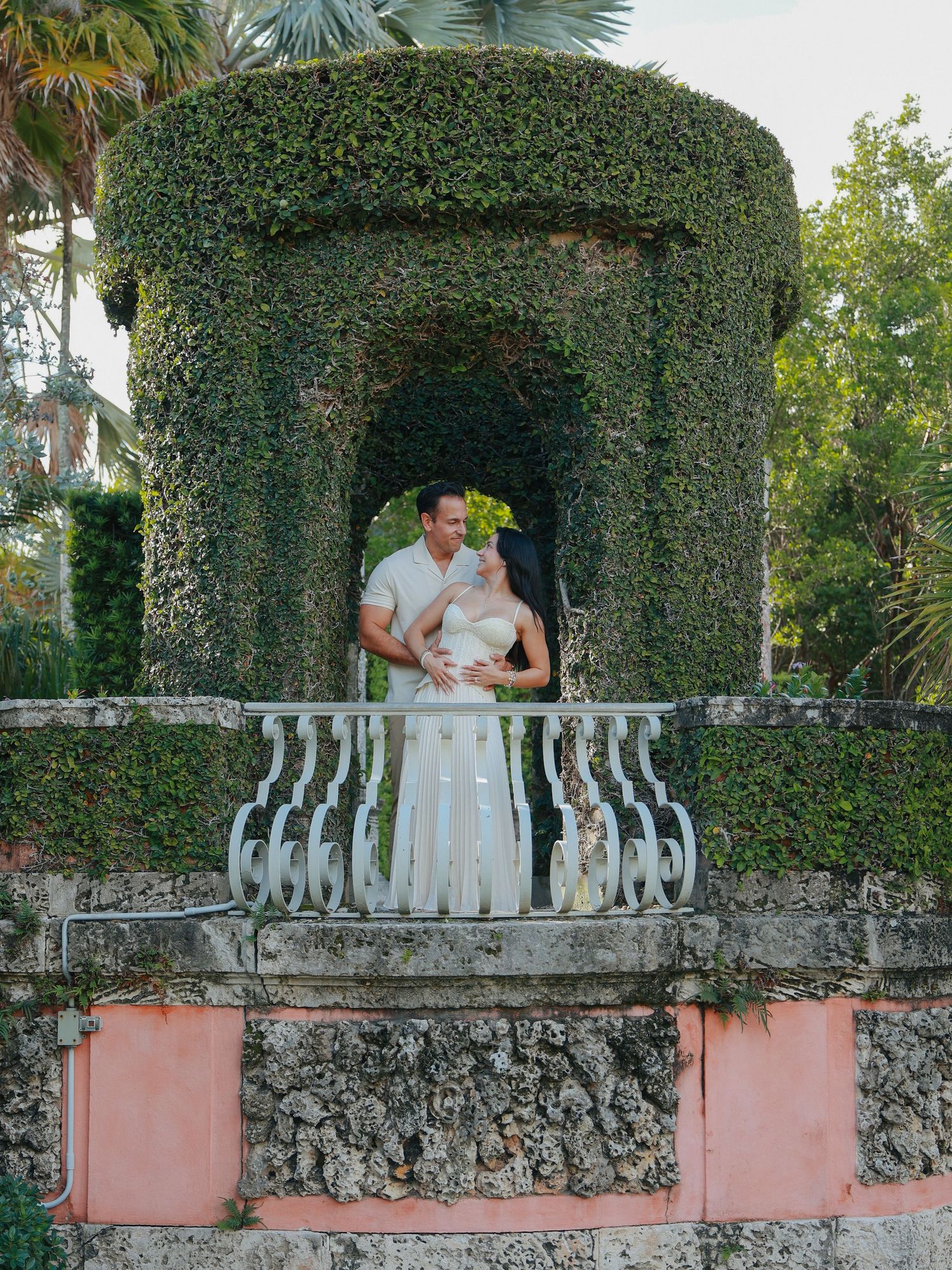 Bride and groom embracing on ivy-covered balcony at Vizcaya Museum and Gardens in Miami.