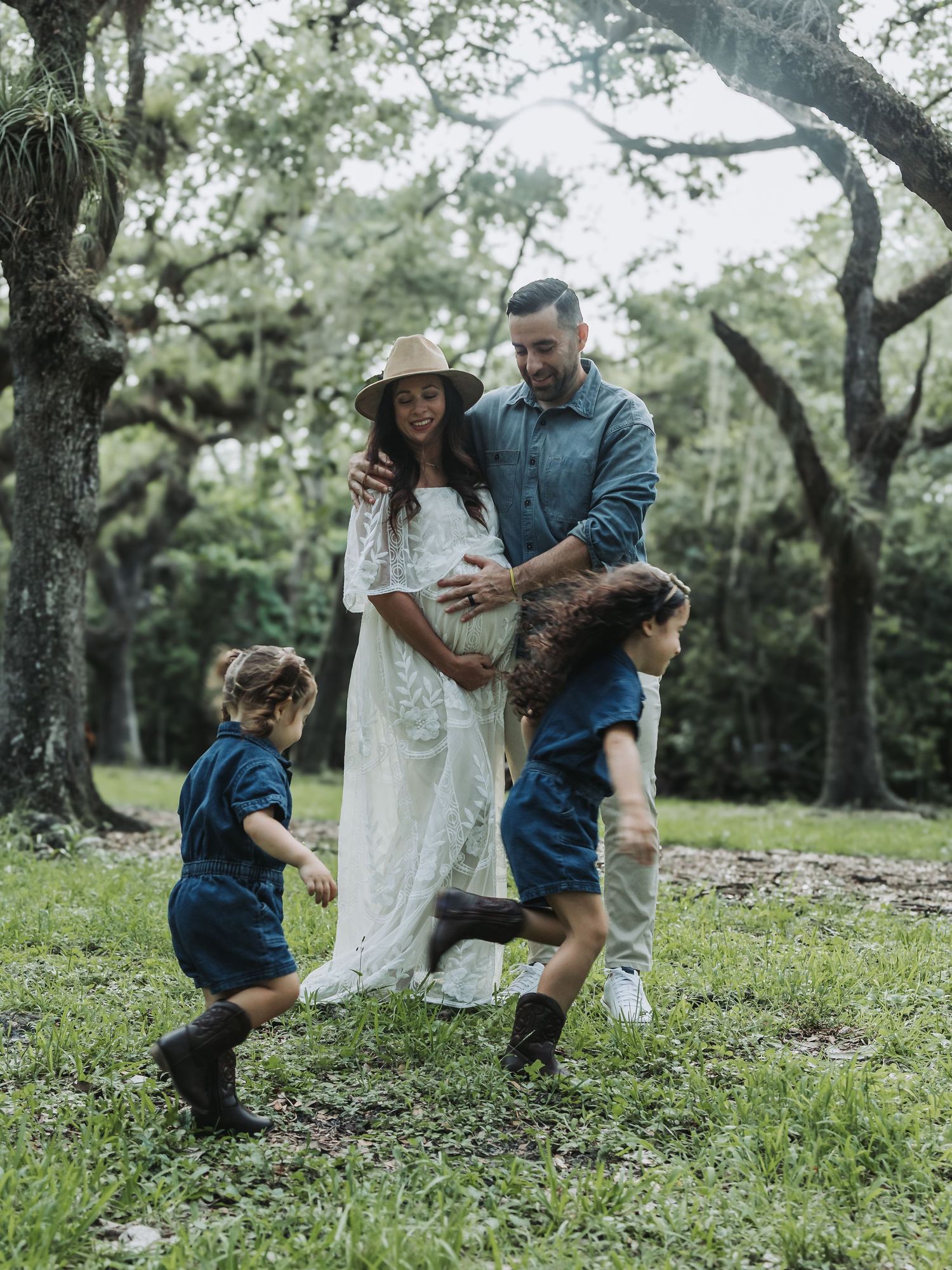 Happy family with pregnant mother, father, and two children in lush green park.