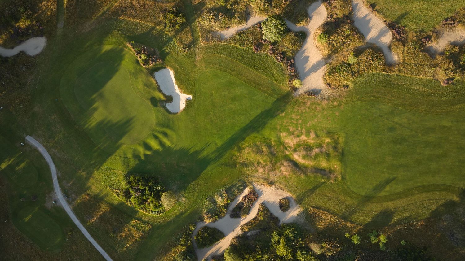 Aerial view of a golf course featuring lush green fairways and white sand bunkers.