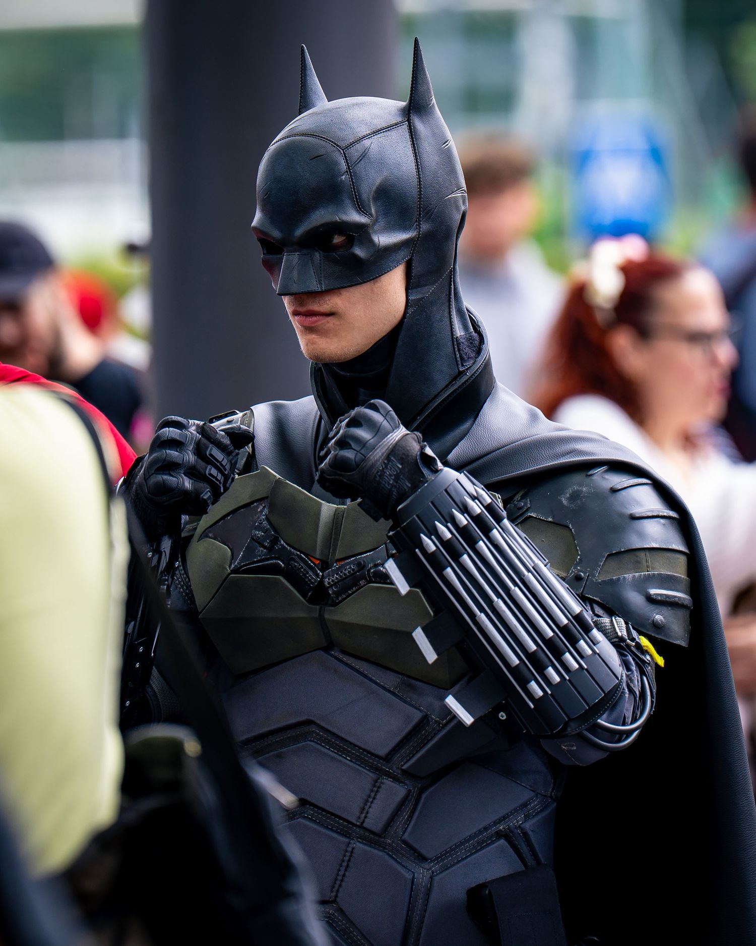 Person in detailed Batman cosplay costume with armored suit and gauntlets at a comic convention.