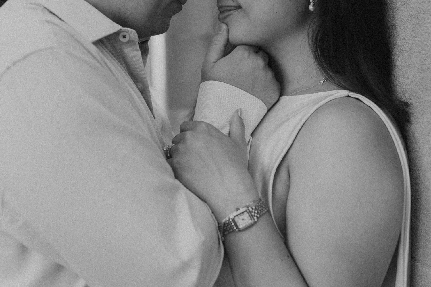 Black and white photo of a couple sharing a romantic moment, holding hands closely together.