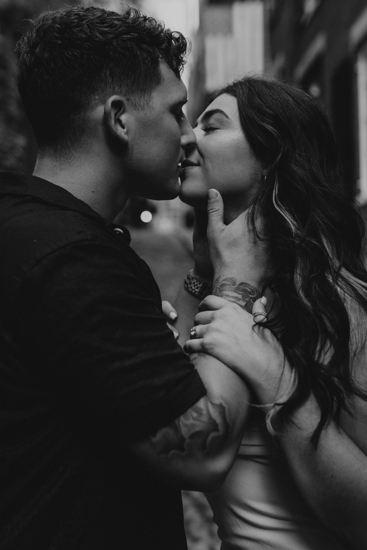 Black and white romantic photo of a couple sharing an intimate kiss during their urban engagement session.
