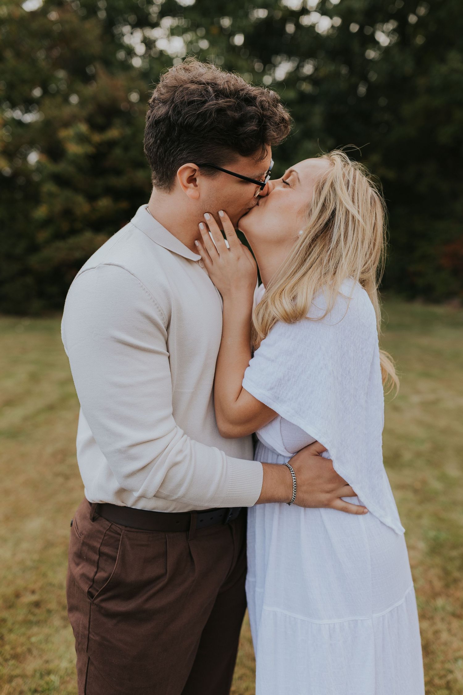 Romantic couple sharing a kiss outdoors during their engagement photography session in nature.