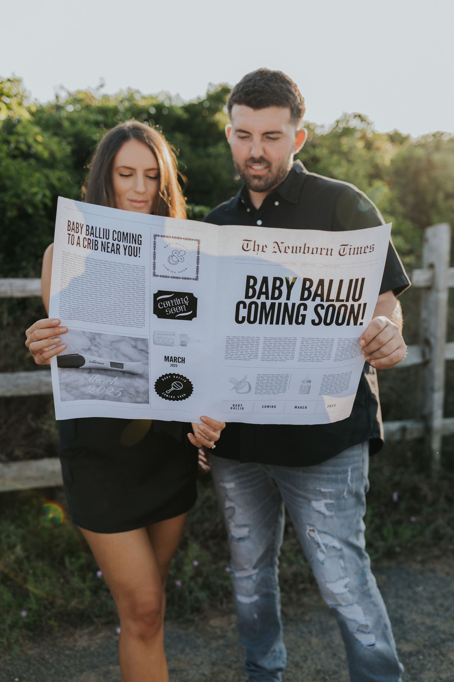 Couple reading a custom newspaper headline announcing Baby Balliu Coming Soon during pregnancy reveal.