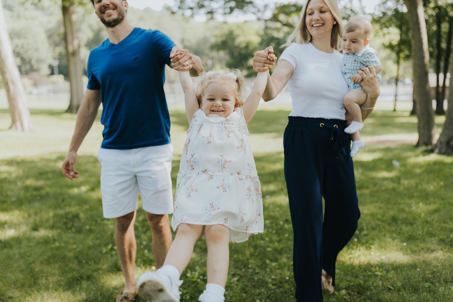 Happy family with two children playing outdoors in a sunny green park.
