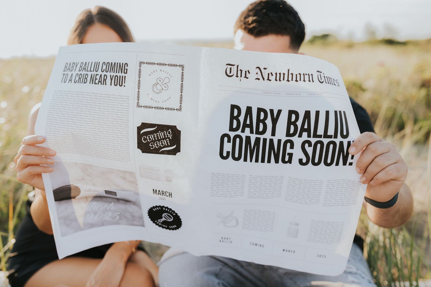 Close-up of couple holding The Newborn Times newspaper announcing Baby Balliu Coming Soon outdoors.