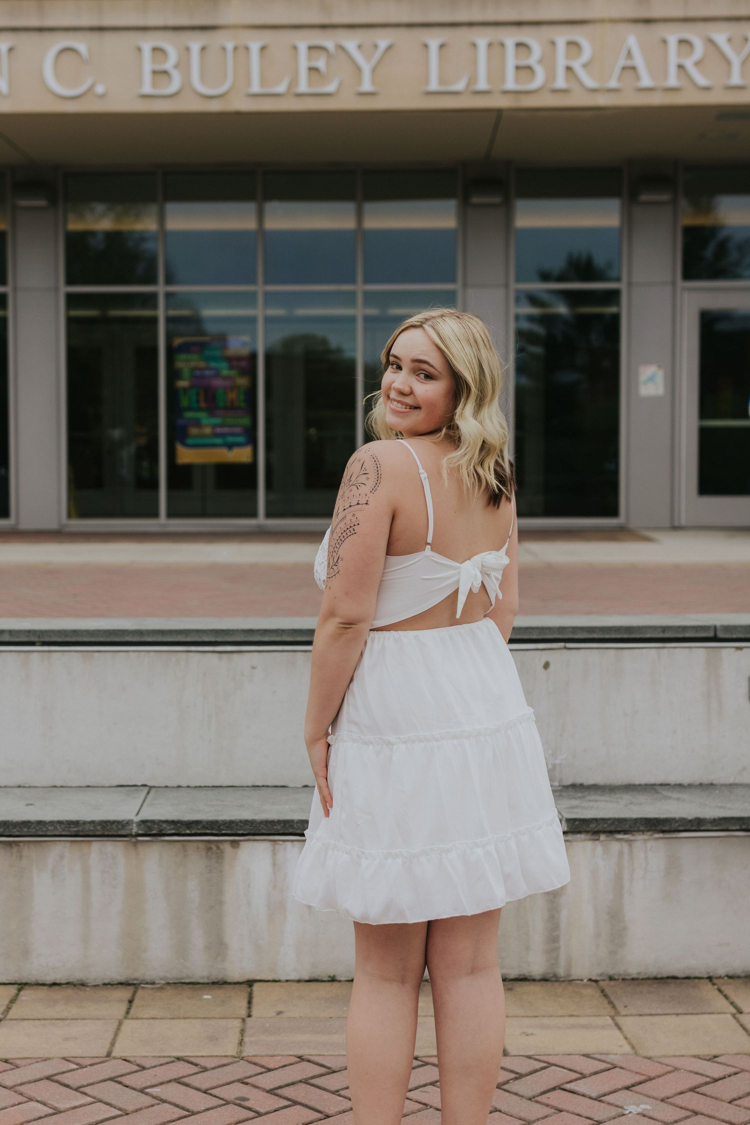 Blonde woman in white sundress posing in front of Buley Library.