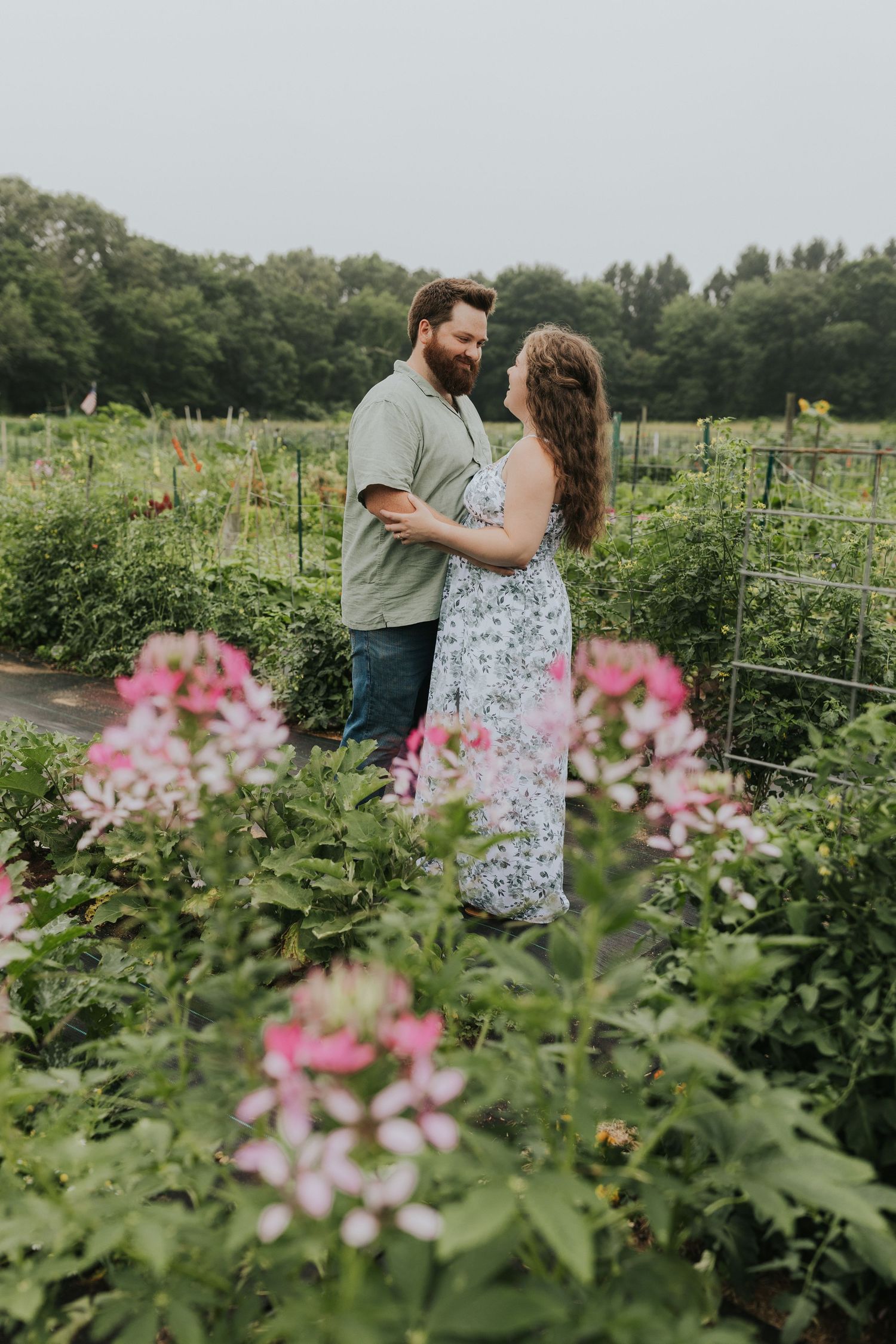 Couple embracing in a lush garden surrounded by colorful blooming flowers.