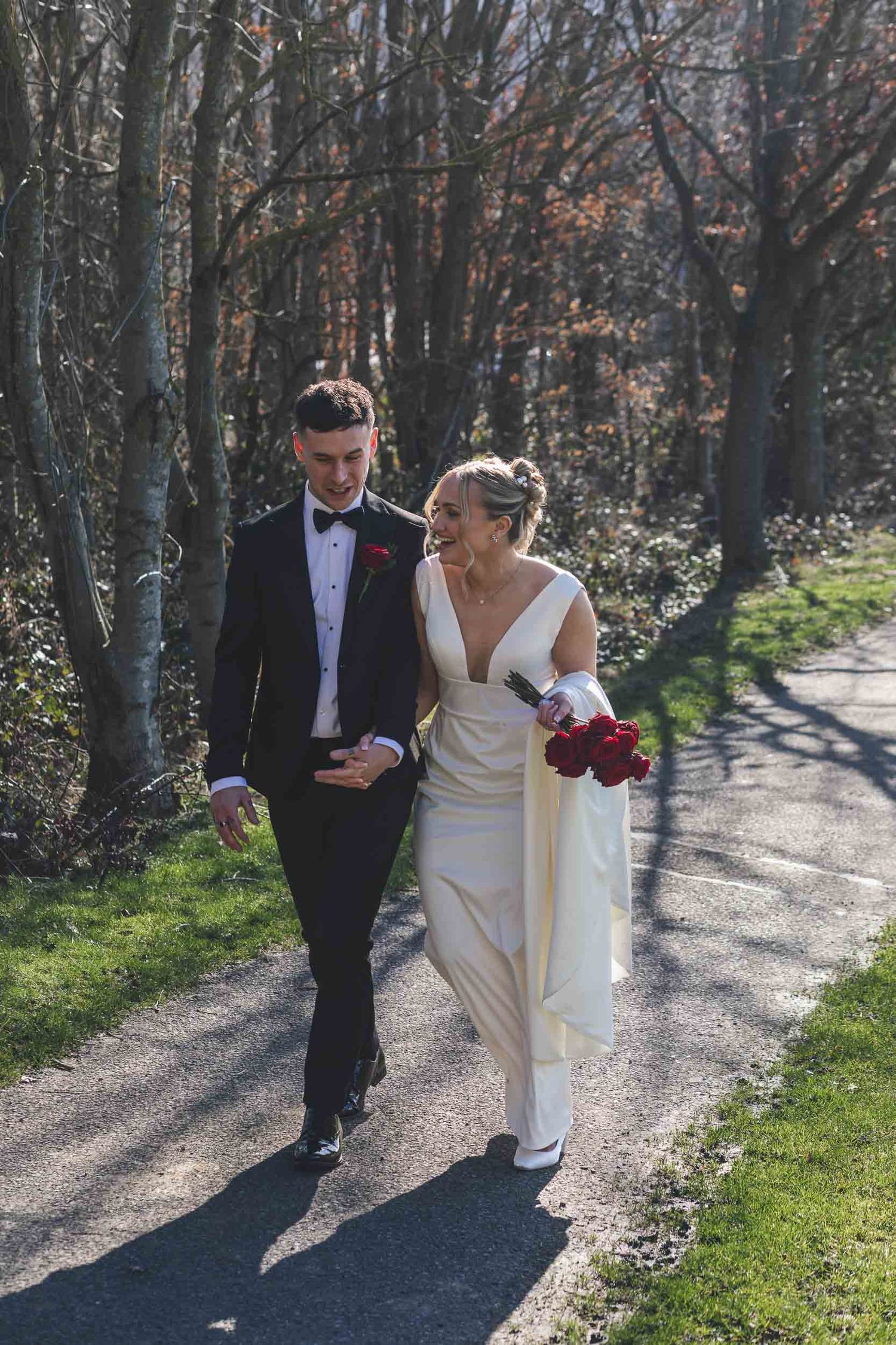 A bride and groom laughing naturally at in the grounds of Hollins Hall wedding venue near Shipley