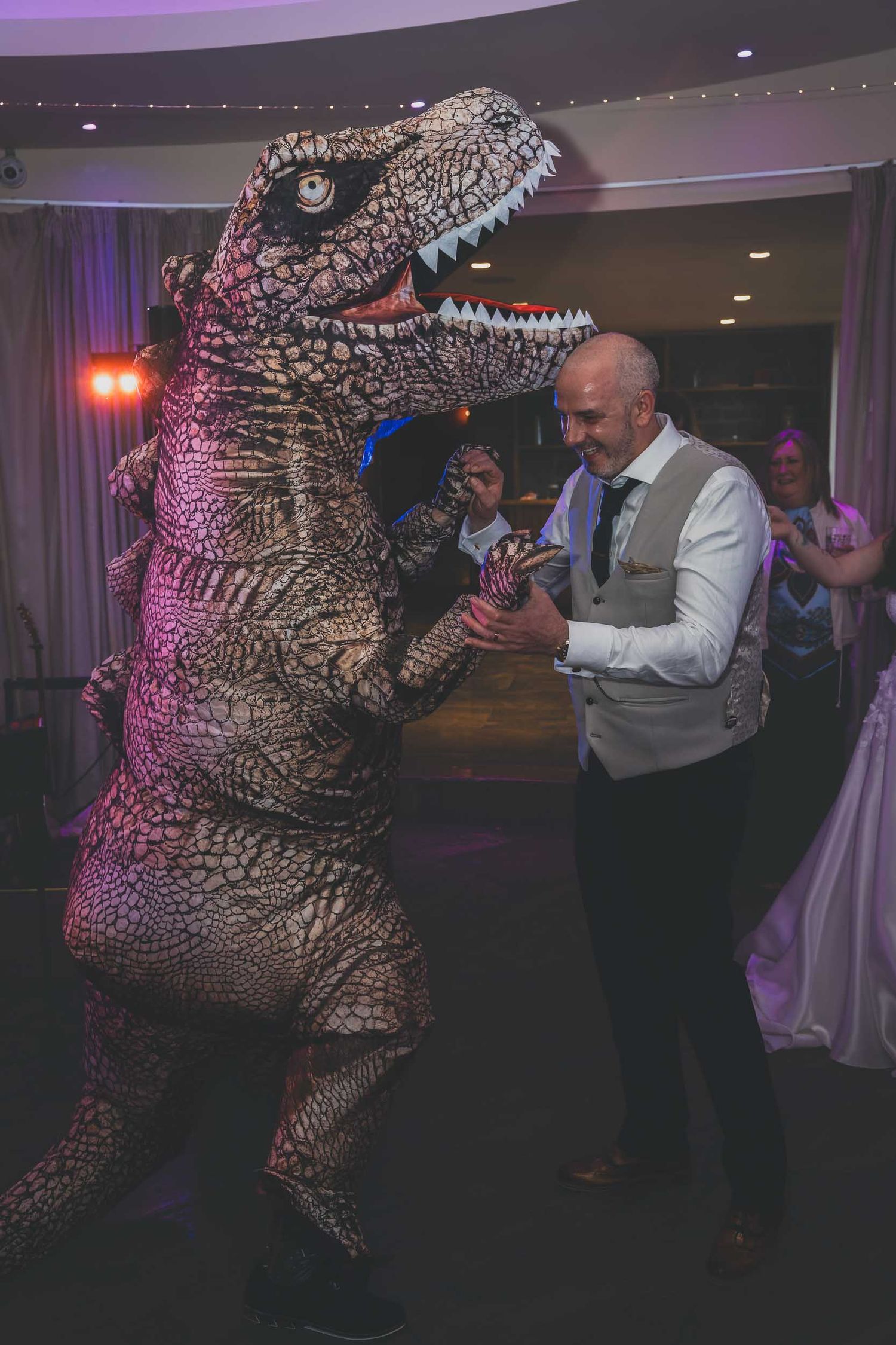 a groom dances with an inflatable dinosaur at a wedding in ribble valley