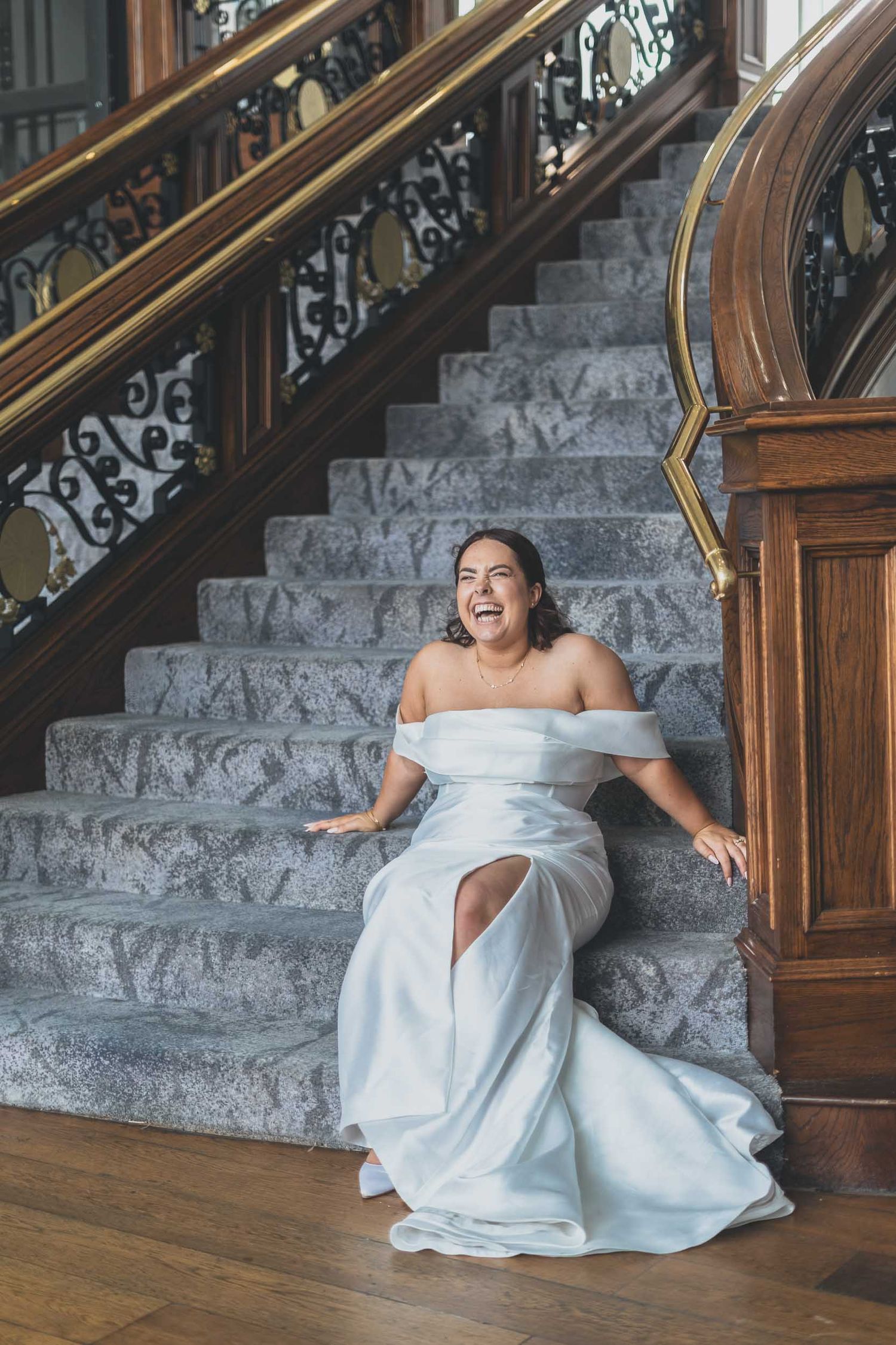 a bride smiles naturally on the staircase of the Titanic Hotel in Liverpool