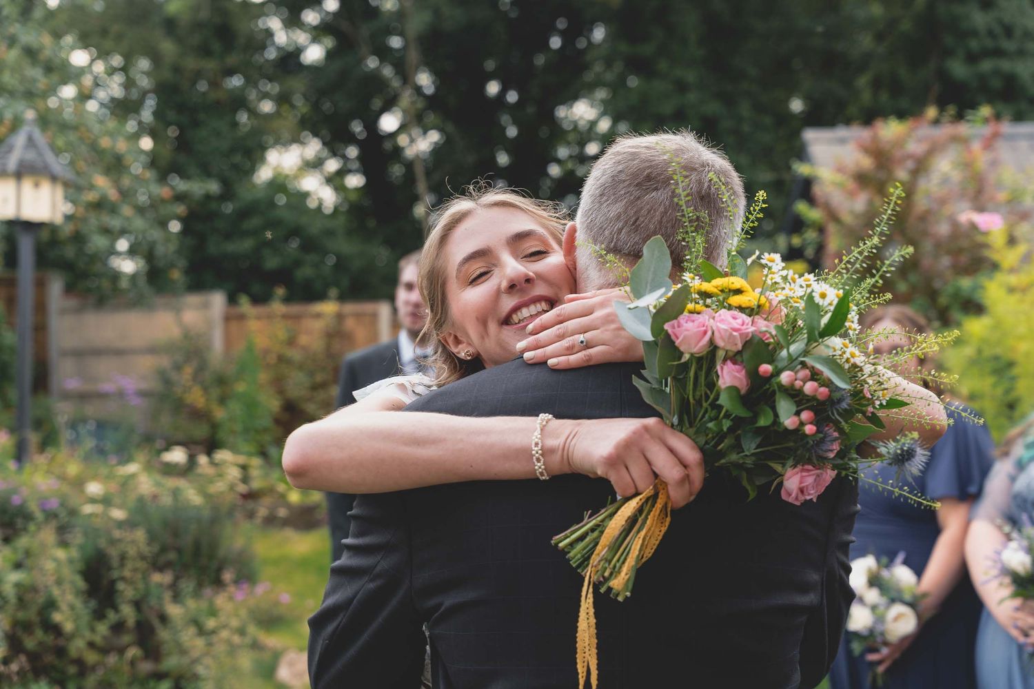 a bride shares an embrace with her father, holding her flowers, at a wedding in parboiled