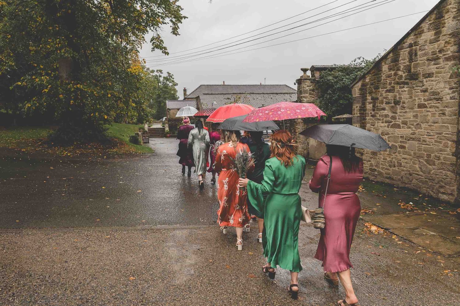 Bridesmaids walk in the rain holding umbrellas in Durham