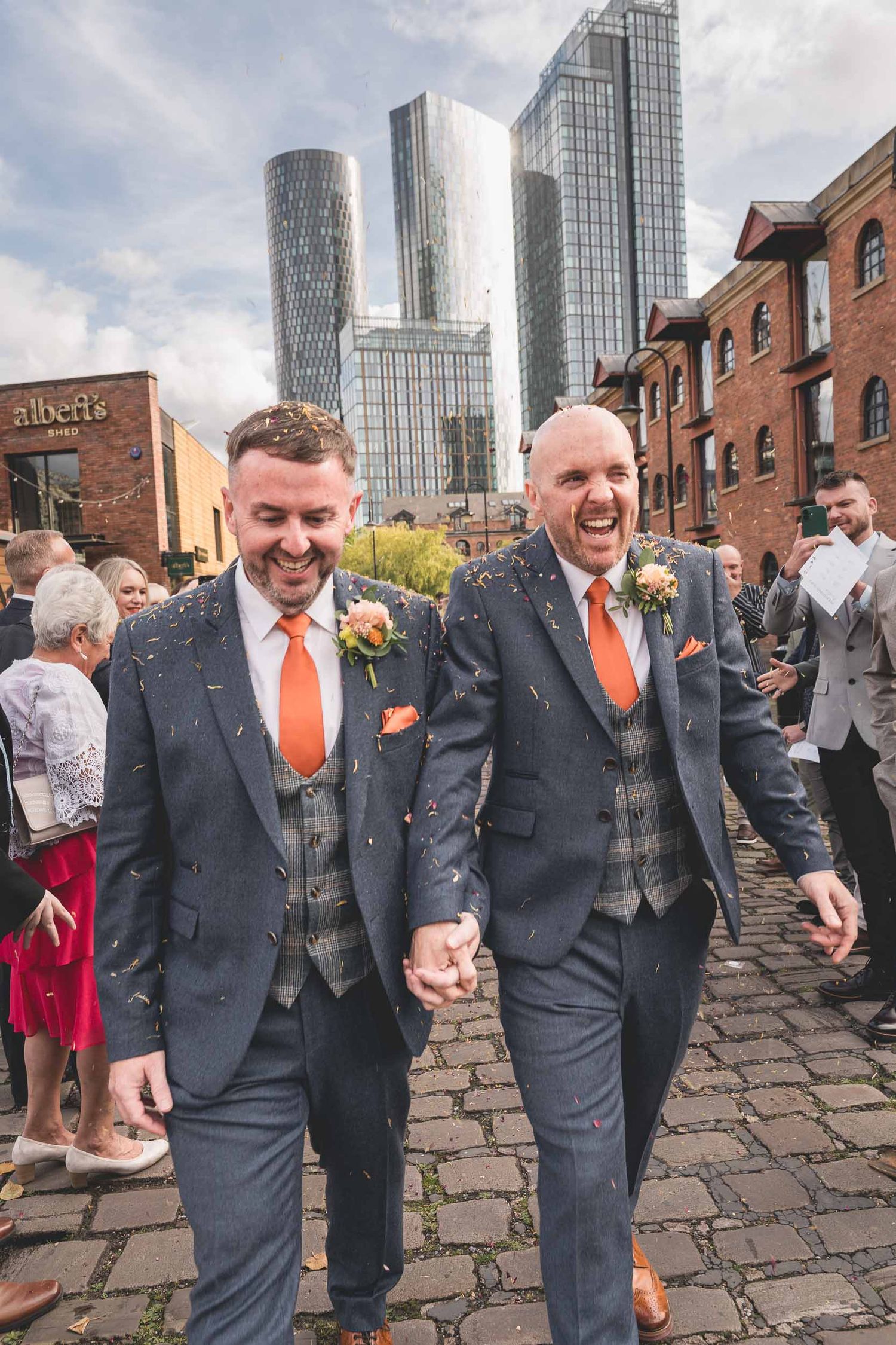 2 grooms walking through confetti at castle field rooms wedding venue in manchester