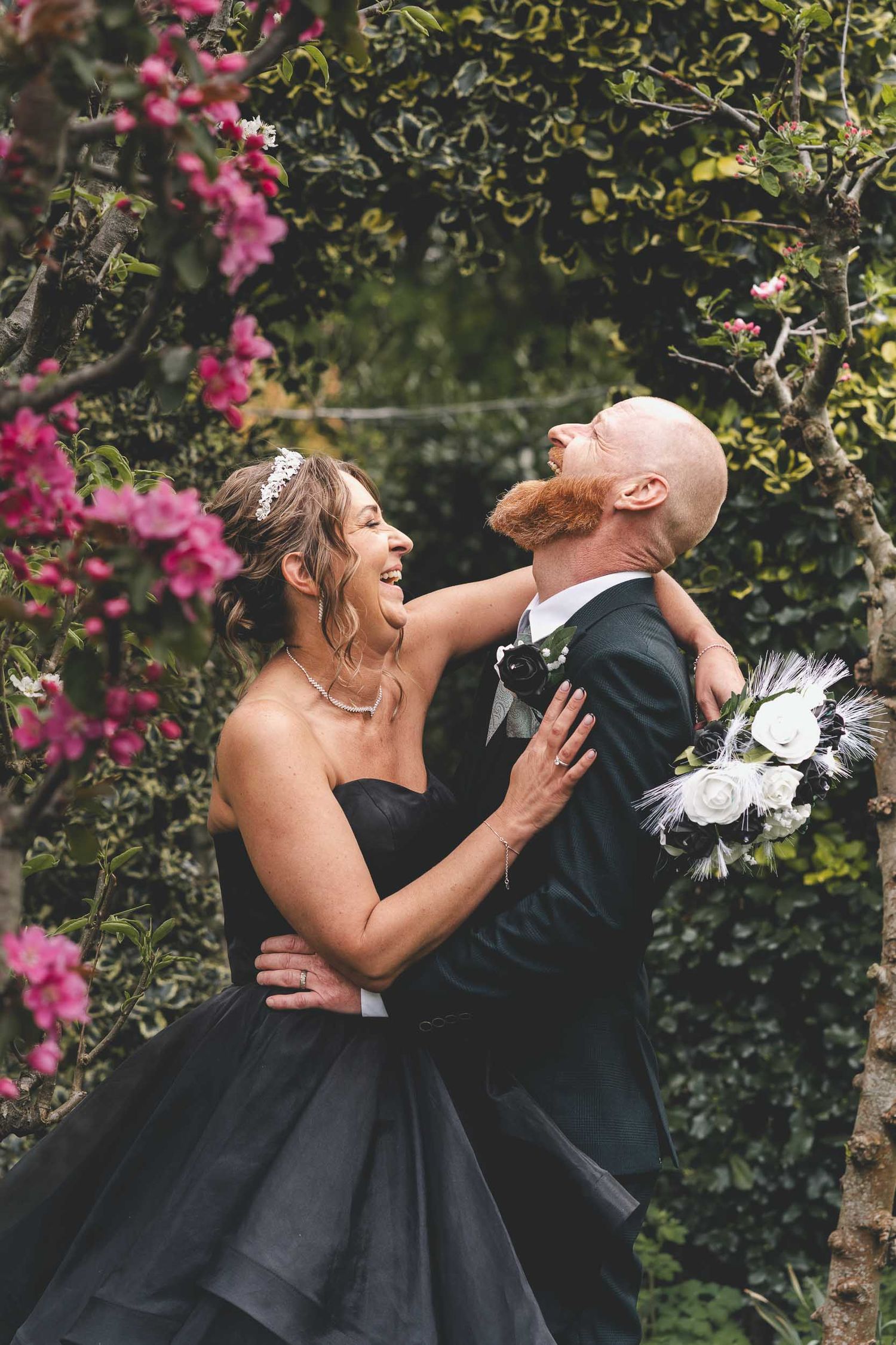 A bride and groom laugh naturally in the gardens of Hundred House wedding venue in Telford