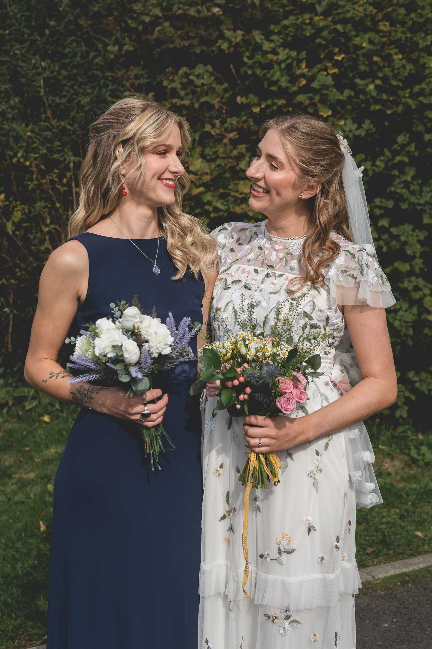 a bride and her sister smile in the sun at their wedding near Wigan