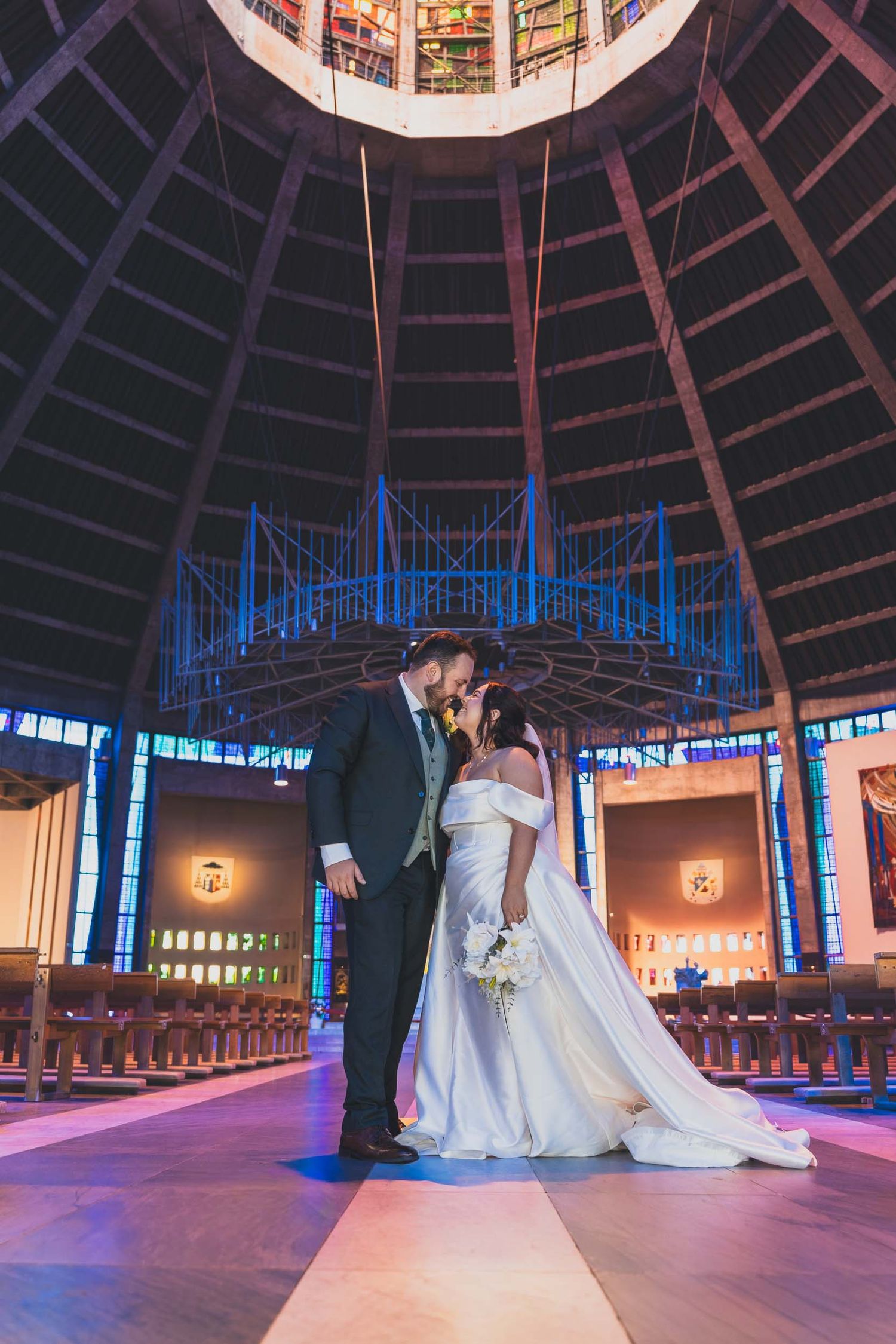 a bride and groom kiss inside the metropolitan cathedral in Liverpool