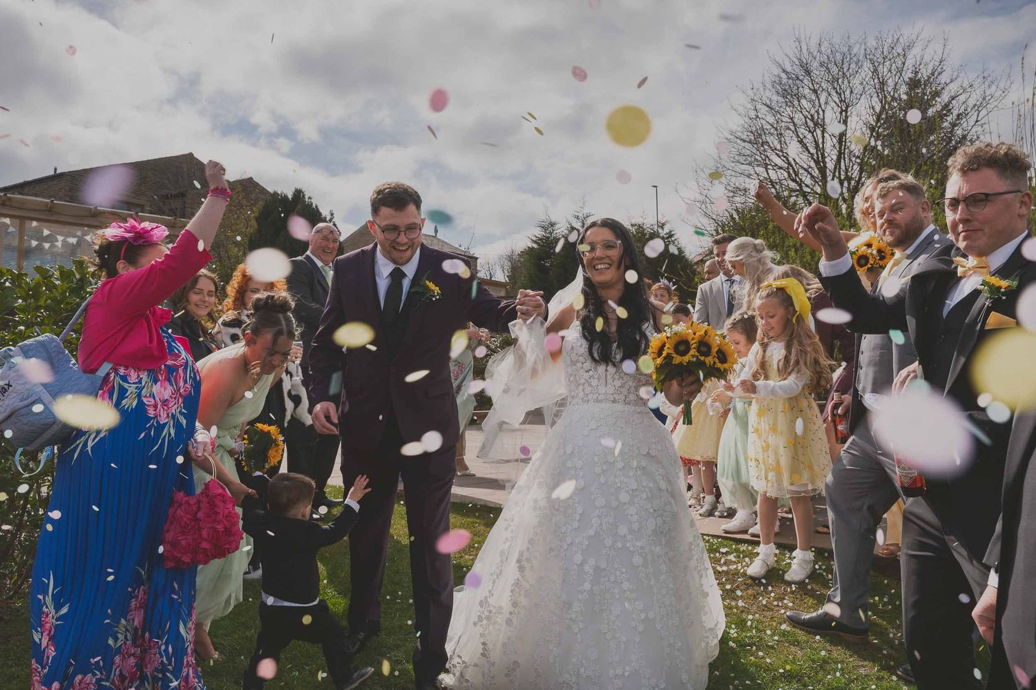 a bride and groom walk through confetti at their wedding in greater manchester