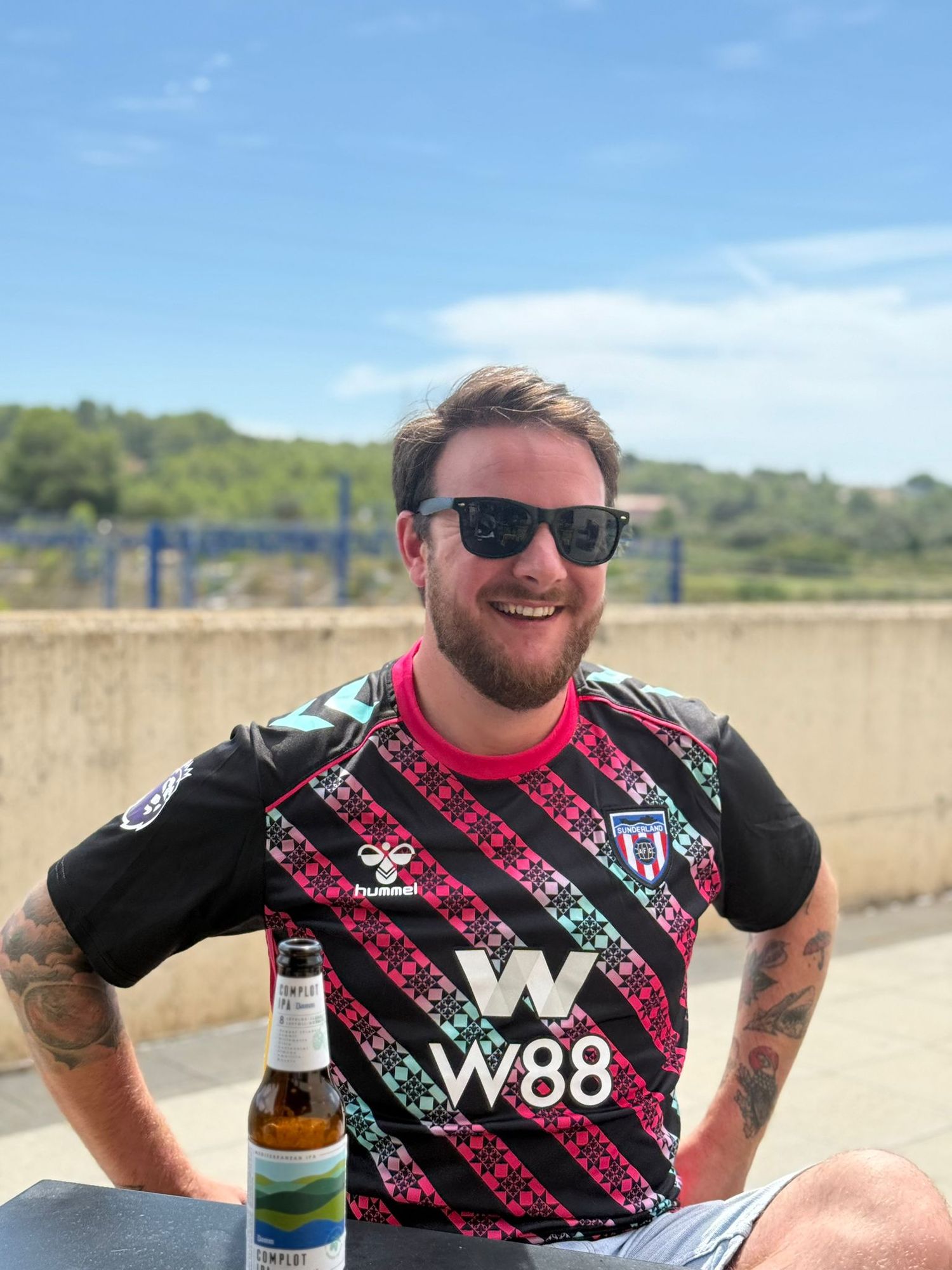 A wedding photographer smiles in the sun wearing a Sunderland football shirt
