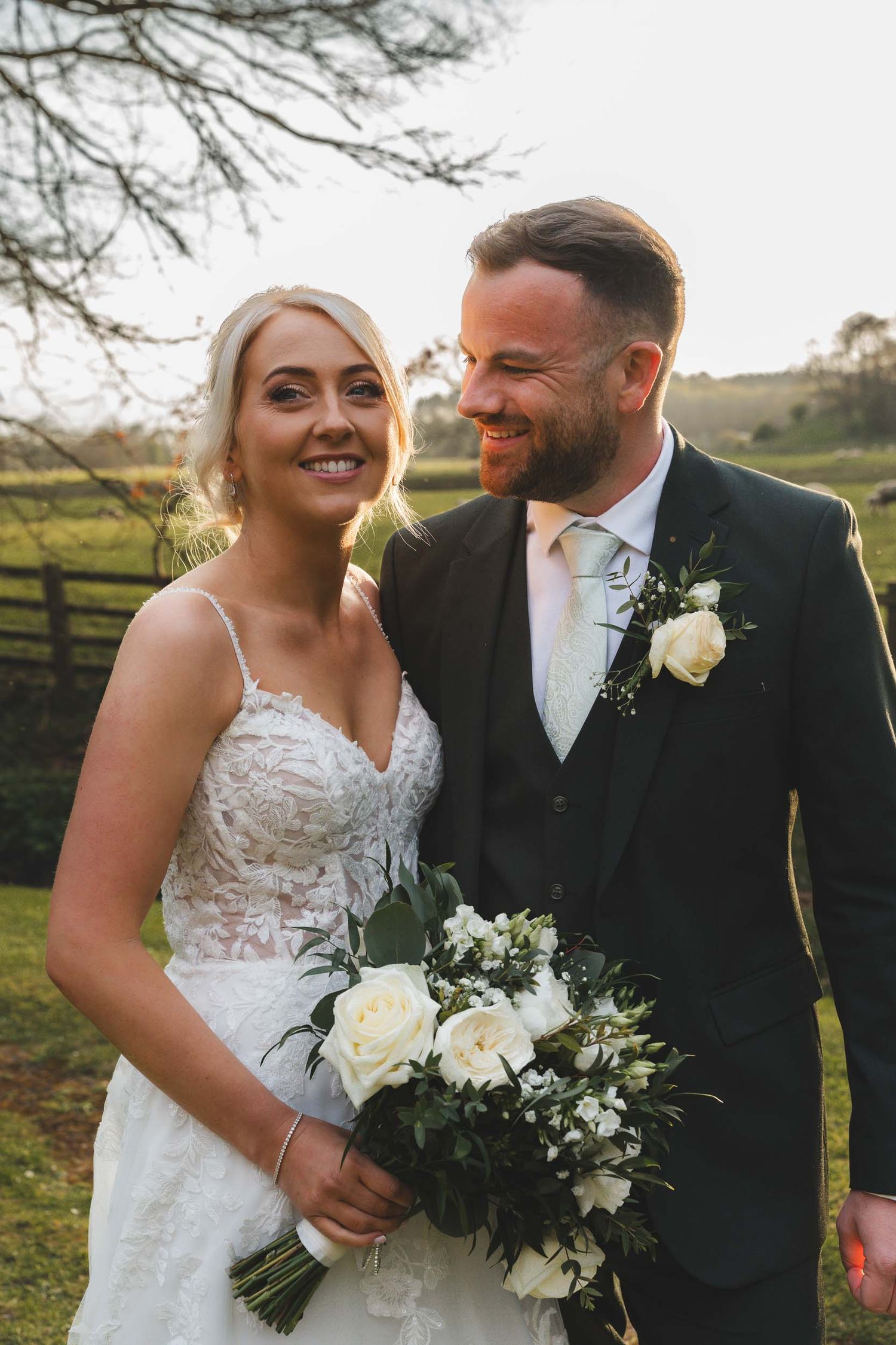 a bride and groom smile naturally as the sun shines behind them at wedding in lancashire