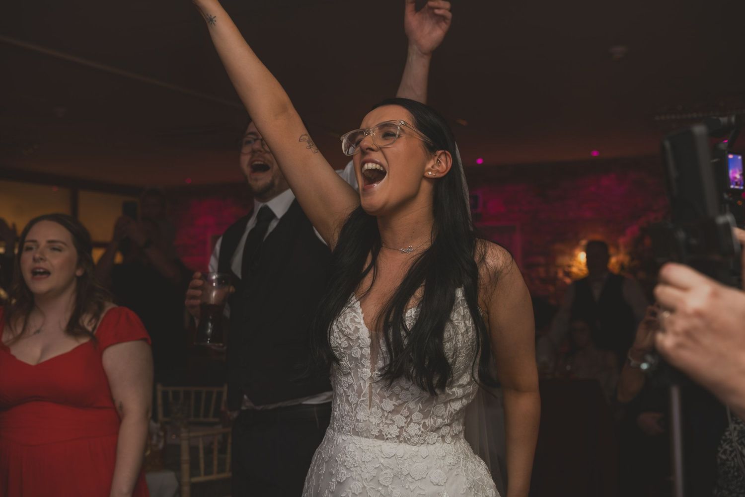 a bride singing with her arms in the air at a wedding in greater Manchester