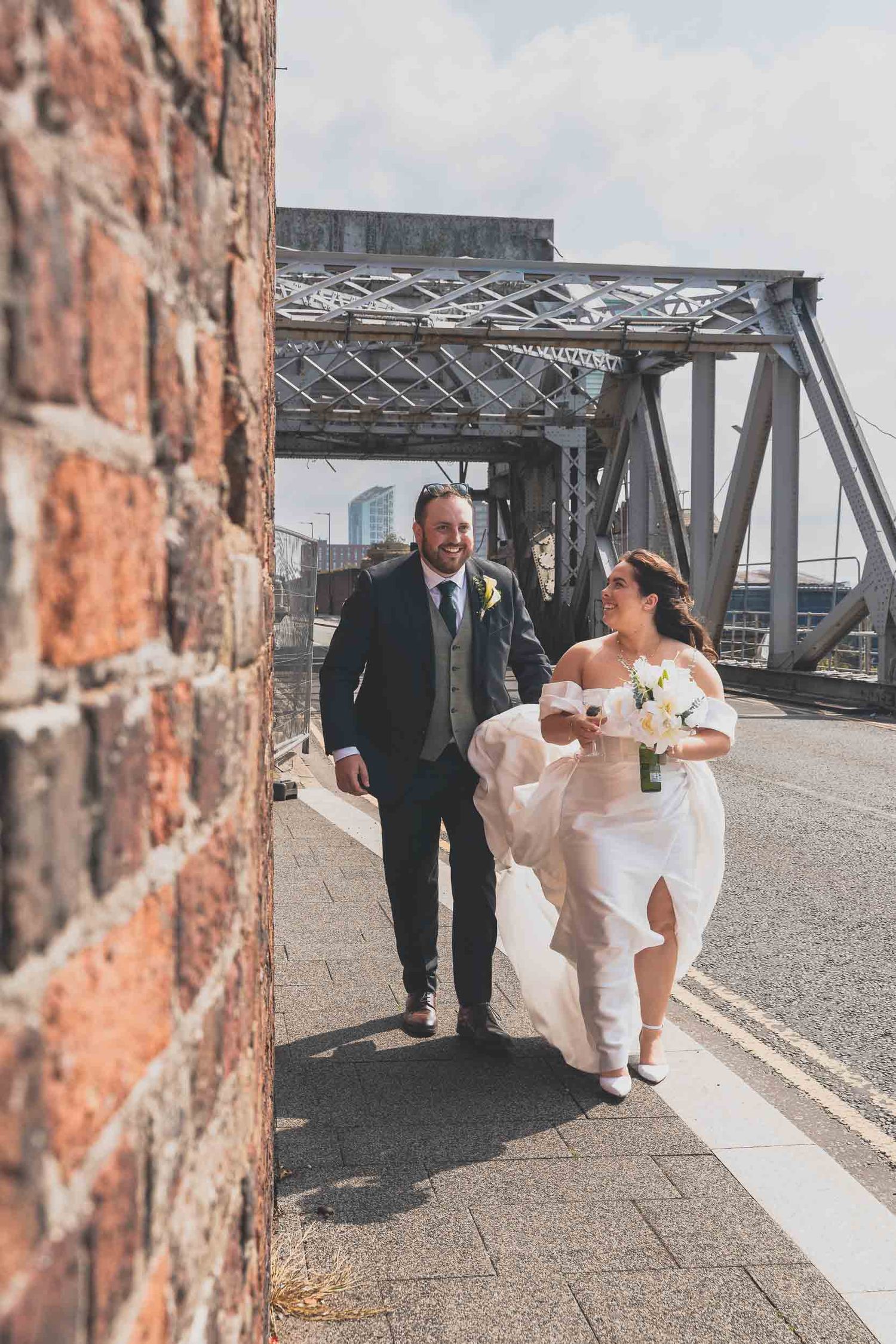 a bride and groom walk along the dockside in Liverpool