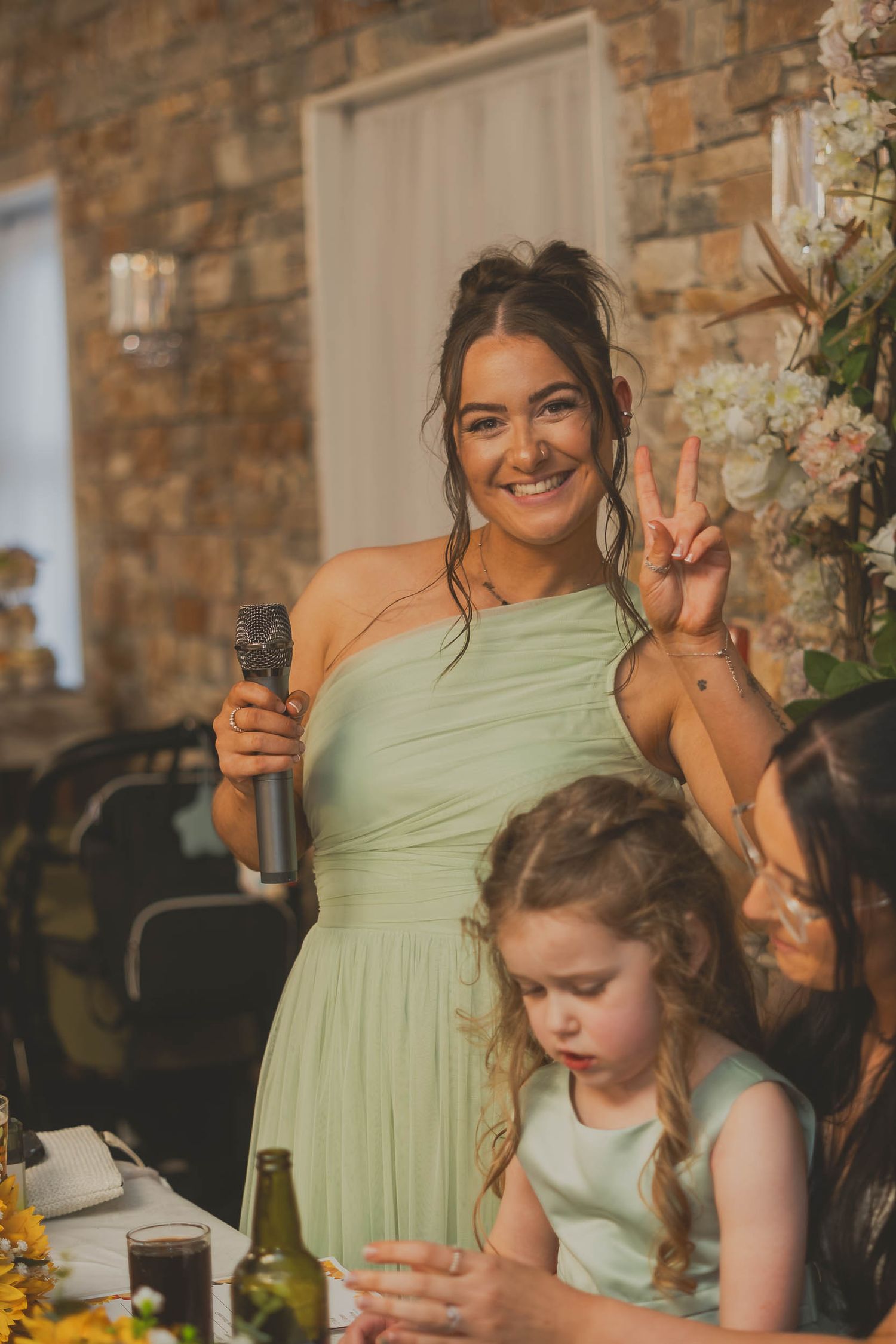 a bridesmaid poses during speeches at a wedding in Greater Manchester