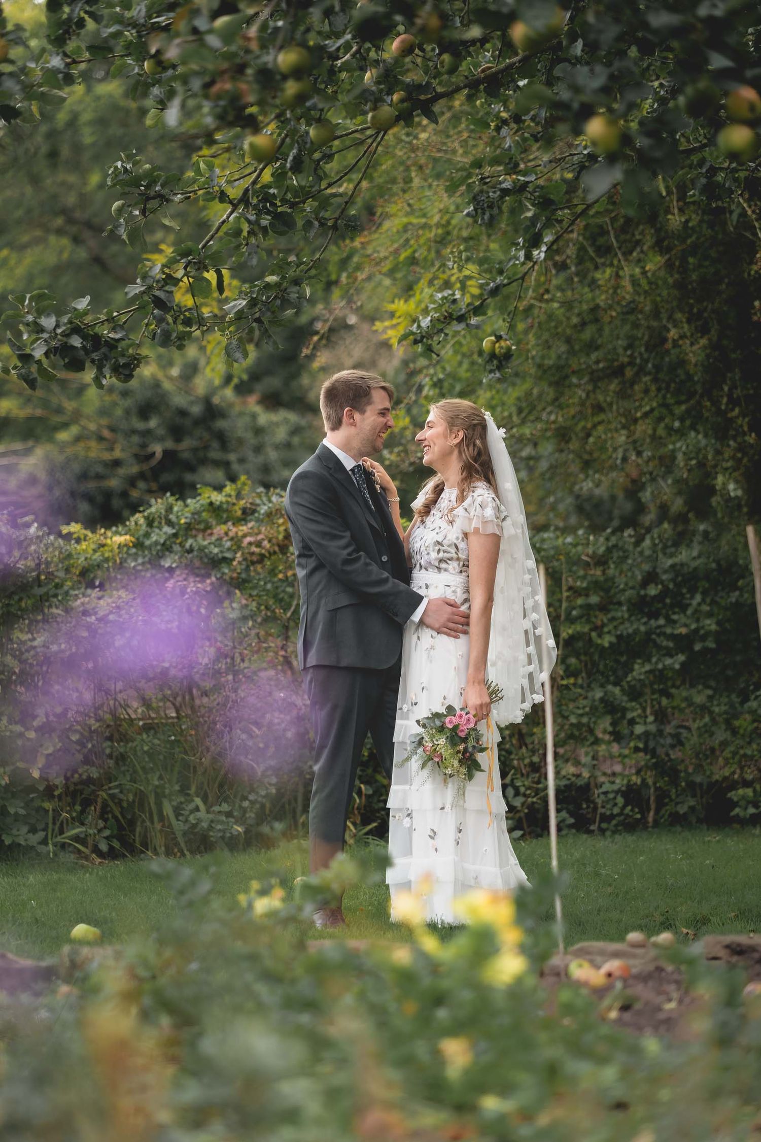 a bride and groom pose among flowers at their wedding in Parbold