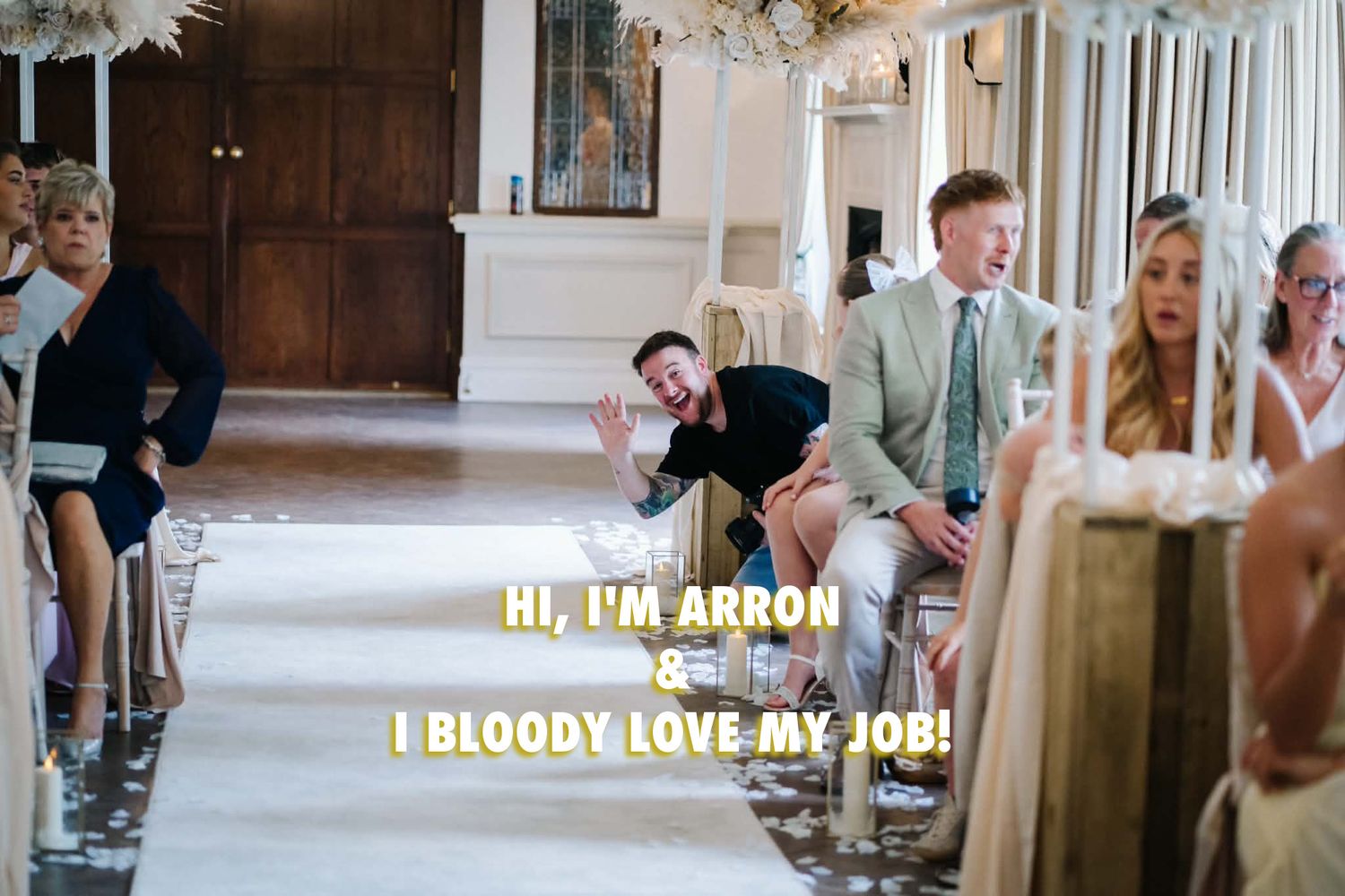 a Wedding photographer smiles and waves from the aisle of a wedding at Bartle Hall wedding venue near Fullwood in Lancashire
