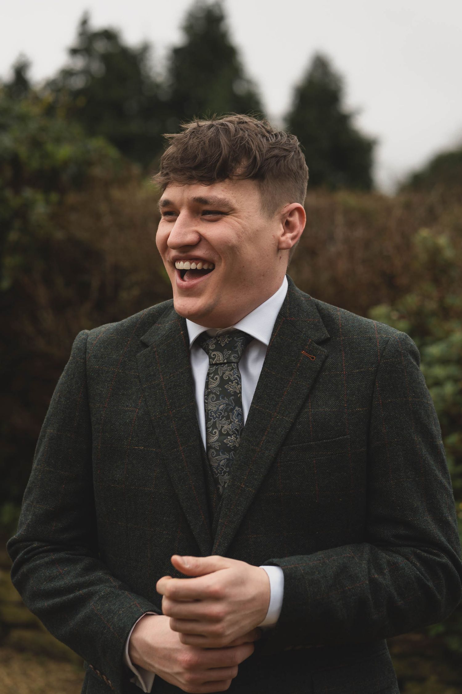 a groom laughs naturally at a wedding in the cotwalds