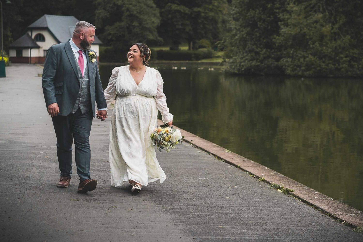 a bride and groom walk by the lake in Victoria park, stoke