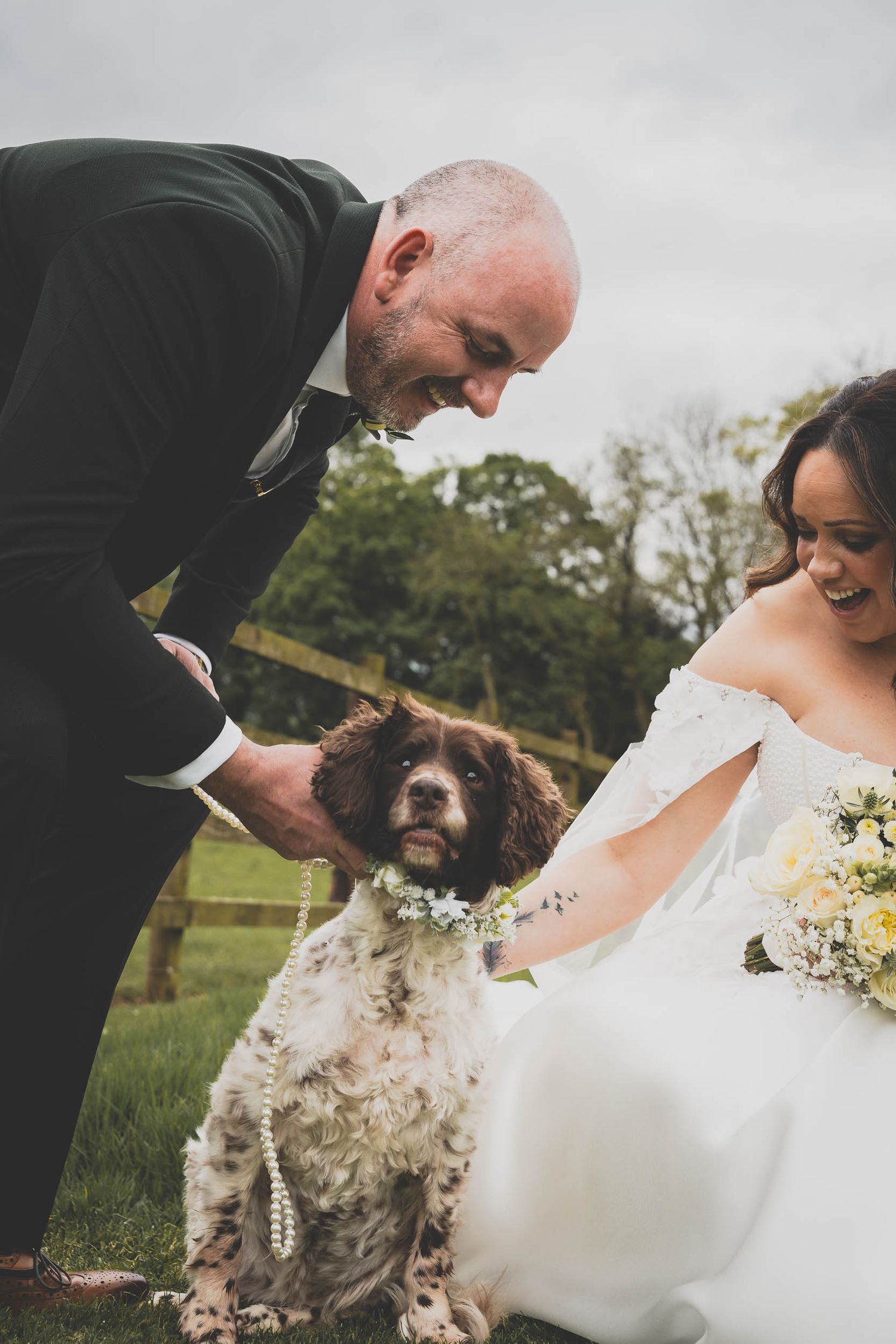 a bride and groom play with their dog at The out barn wedding venue in clitheroe