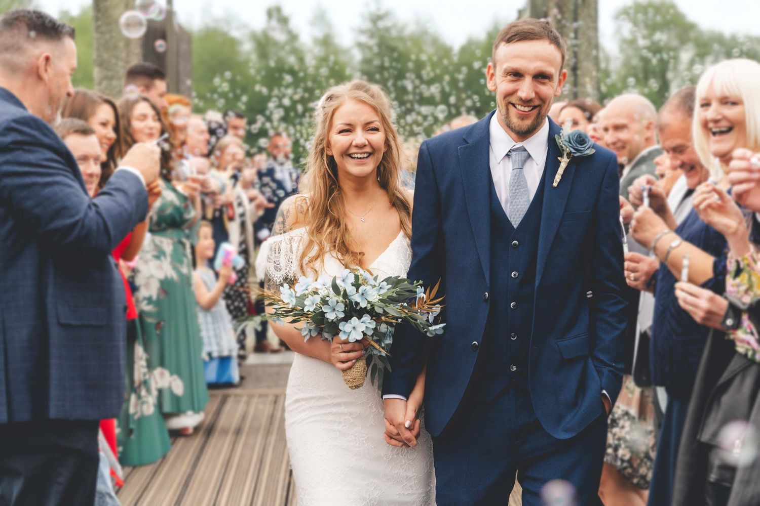 a bride and groom walk through bubbles and confetti in Preston