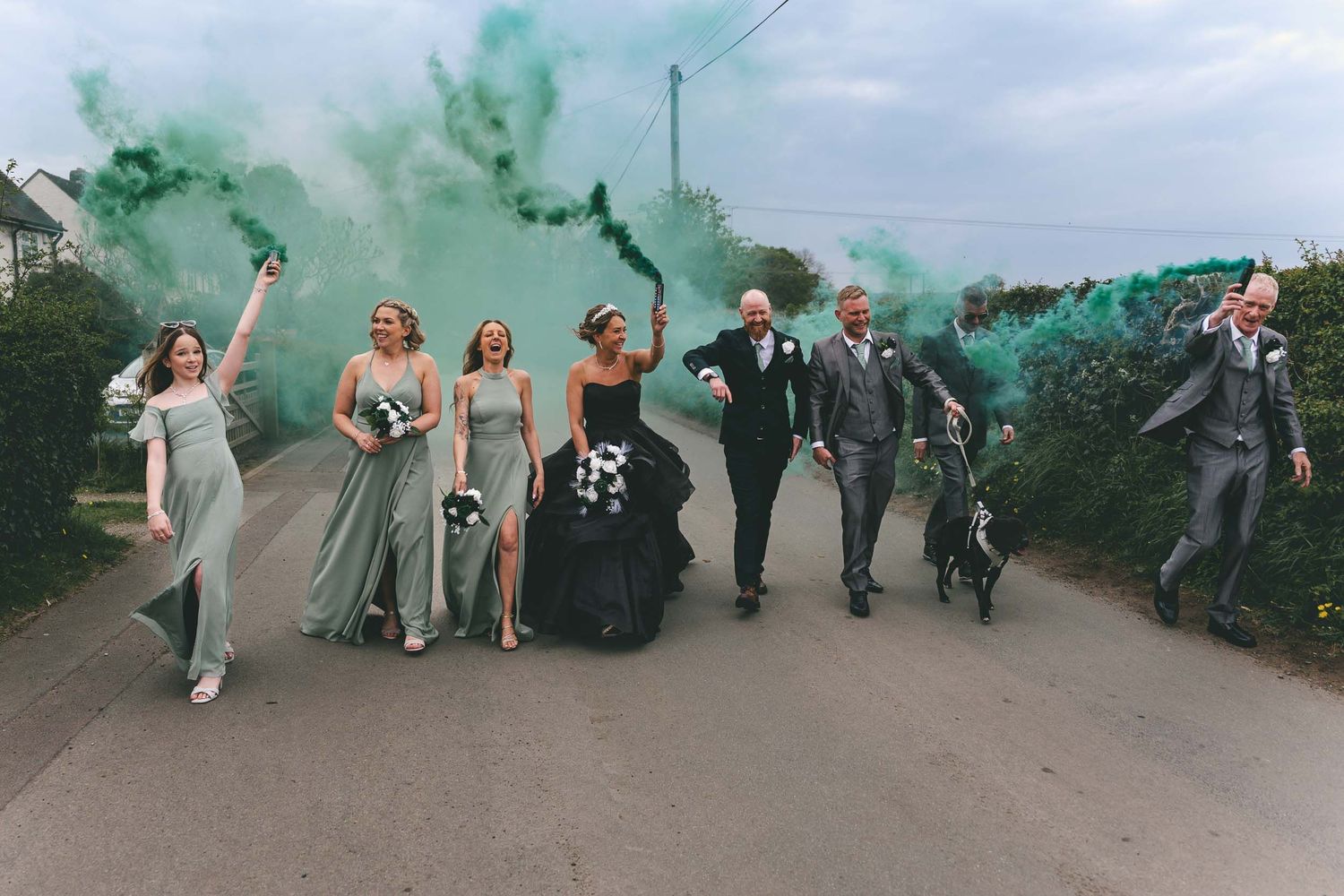 a bride, groom and their wedding party walk naturally with green smoke bombs in Telford