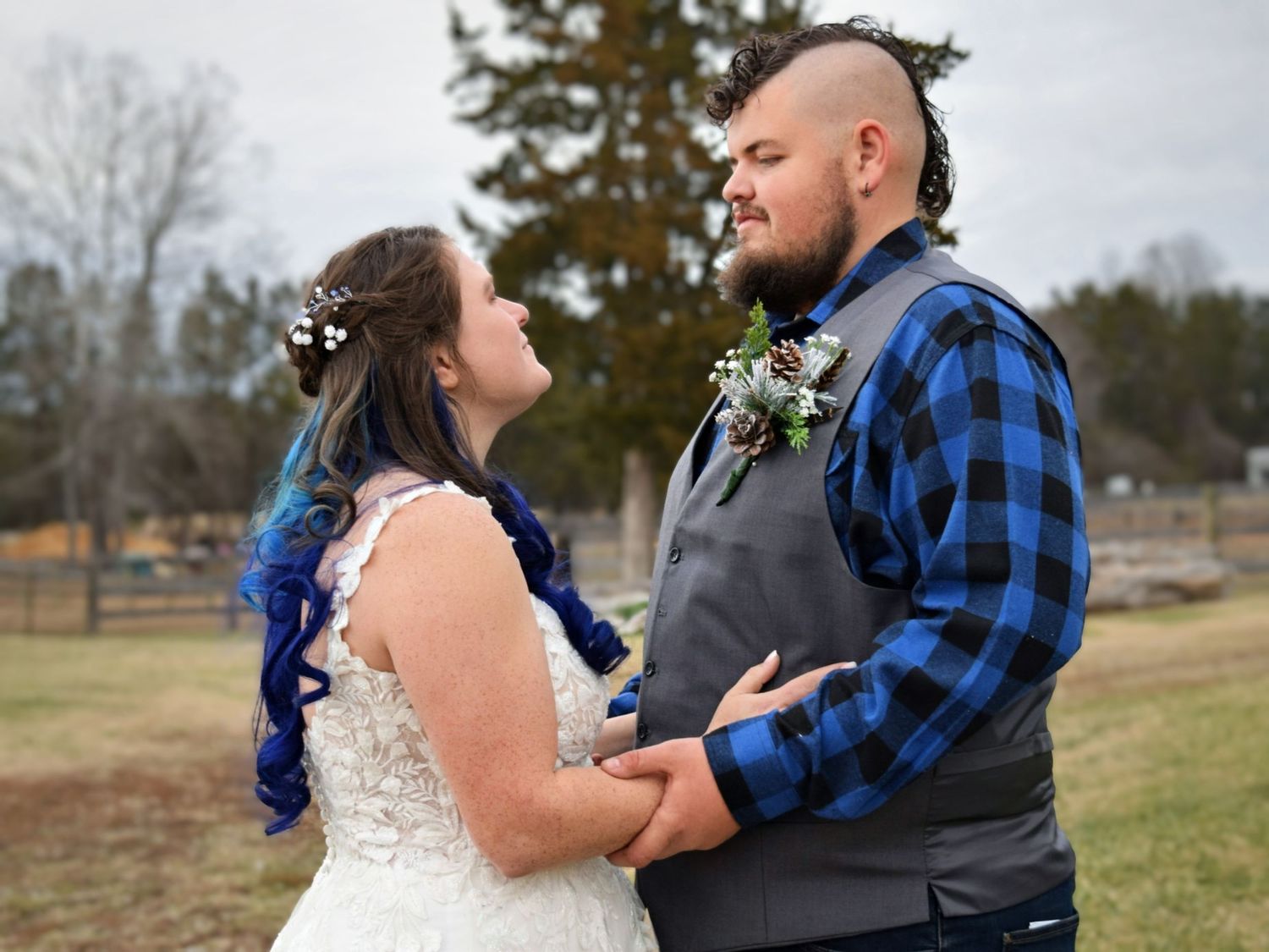 Bride and groom holding hands and gazing at each other lovingly during outdoor winter wedding.