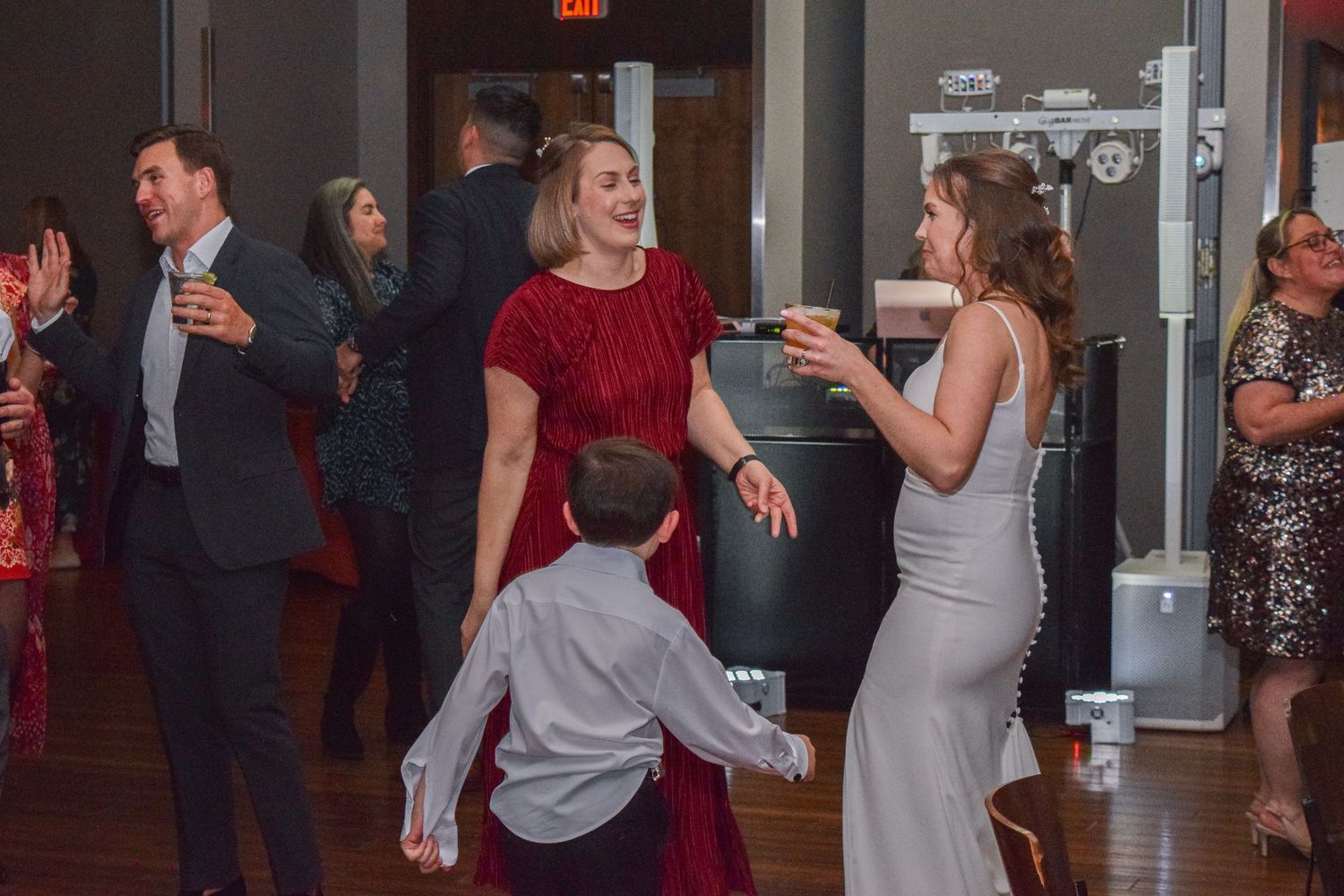 Wedding guests including child dancing together at festive reception celebration.