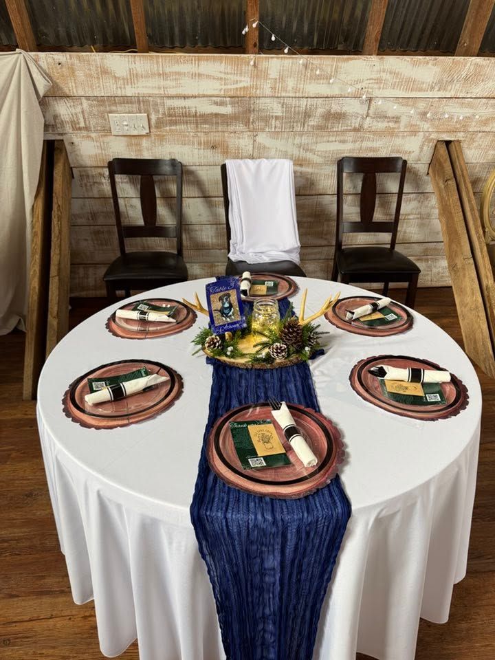 Round banquet table with navy blue runner, wood charger plates, and a festive pine centerpiece.