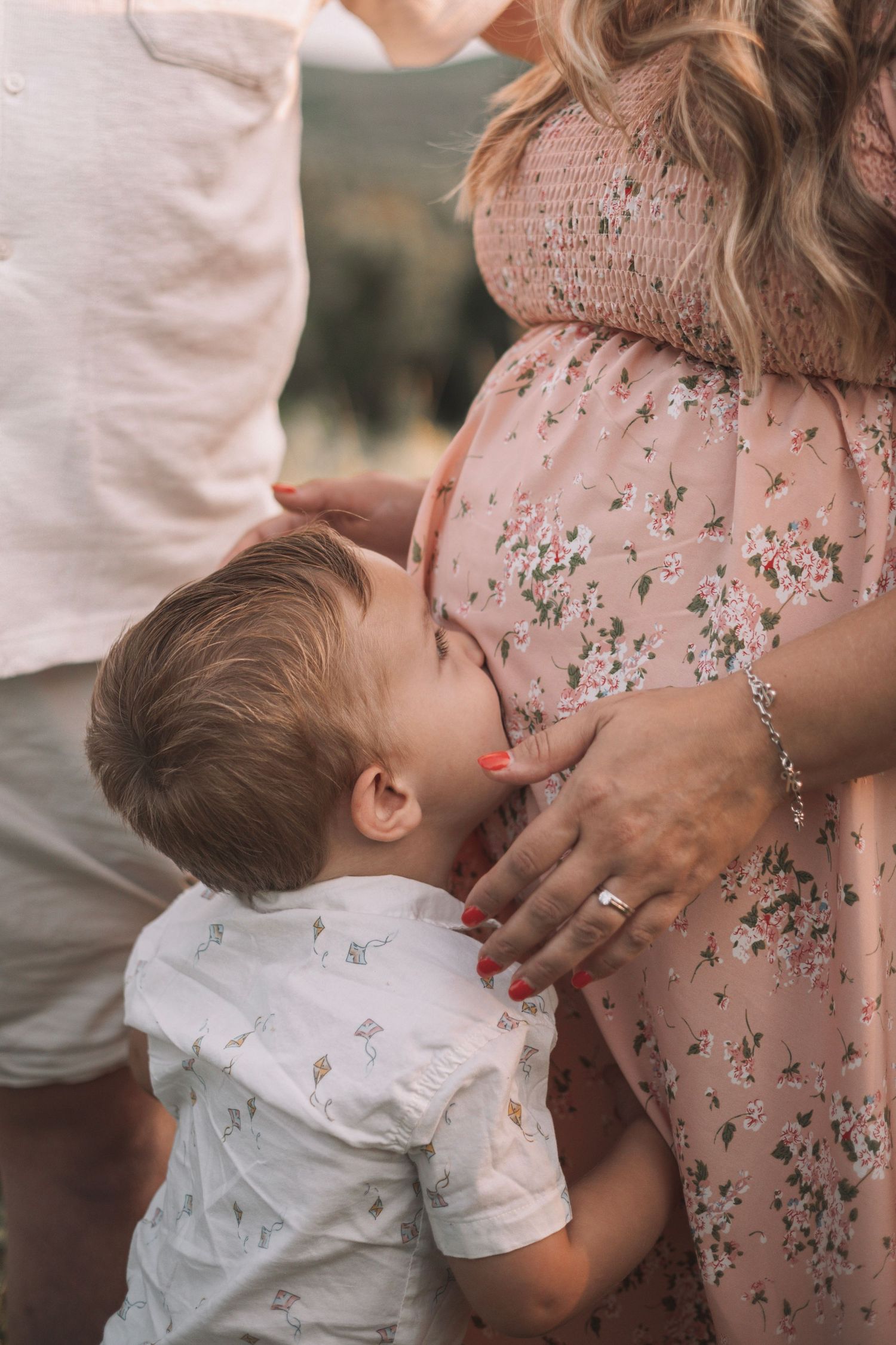Toddler kissing mother's belly during a family maternity session