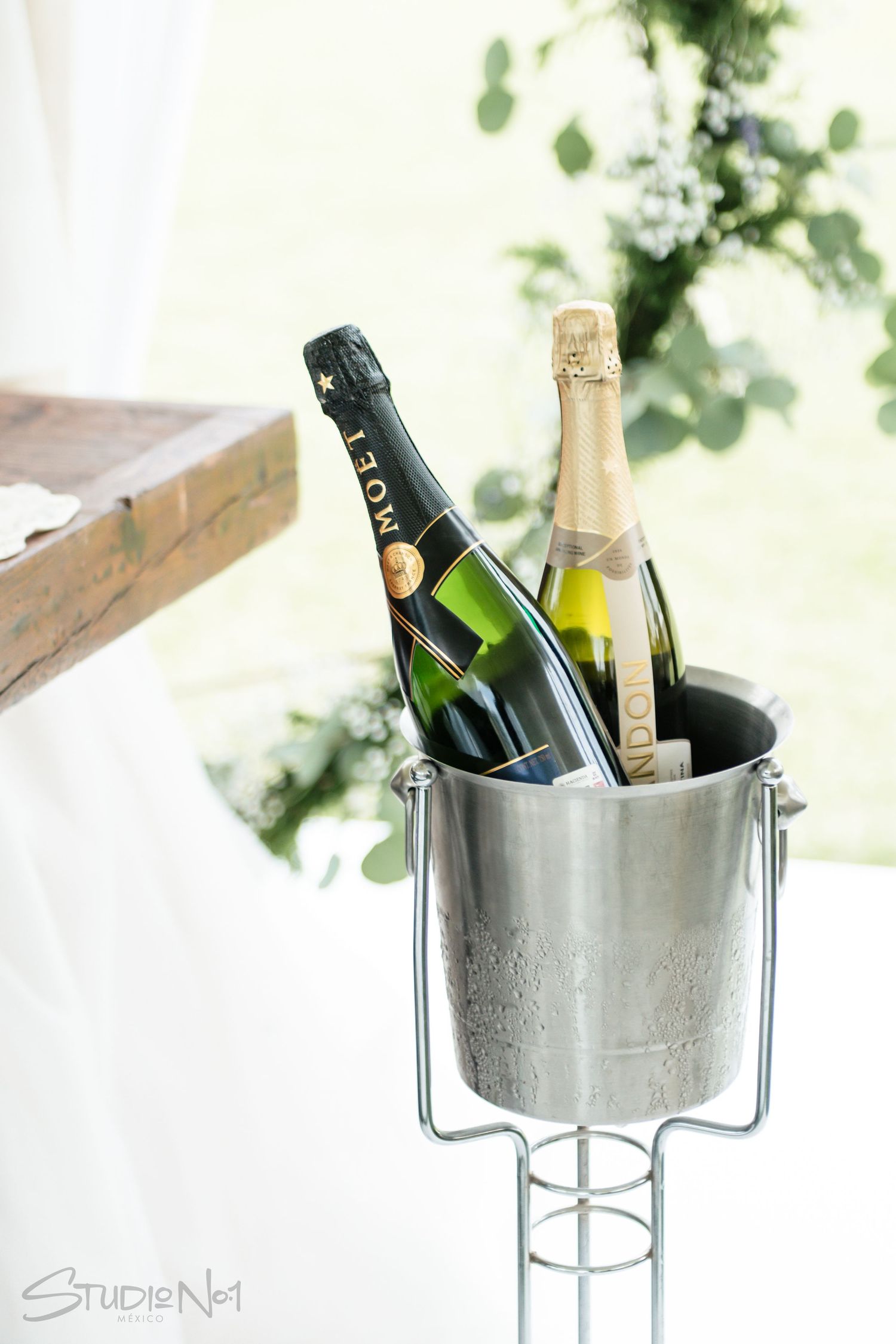 Two Moet champagne bottles chilling in a silver ice bucket at an outdoor wedding reception.