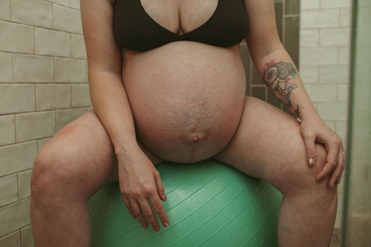 close up shot of expecting moms pregnant belly while she sits on a birthing ball in her shower at her home in Hampton Roads, Virginia.