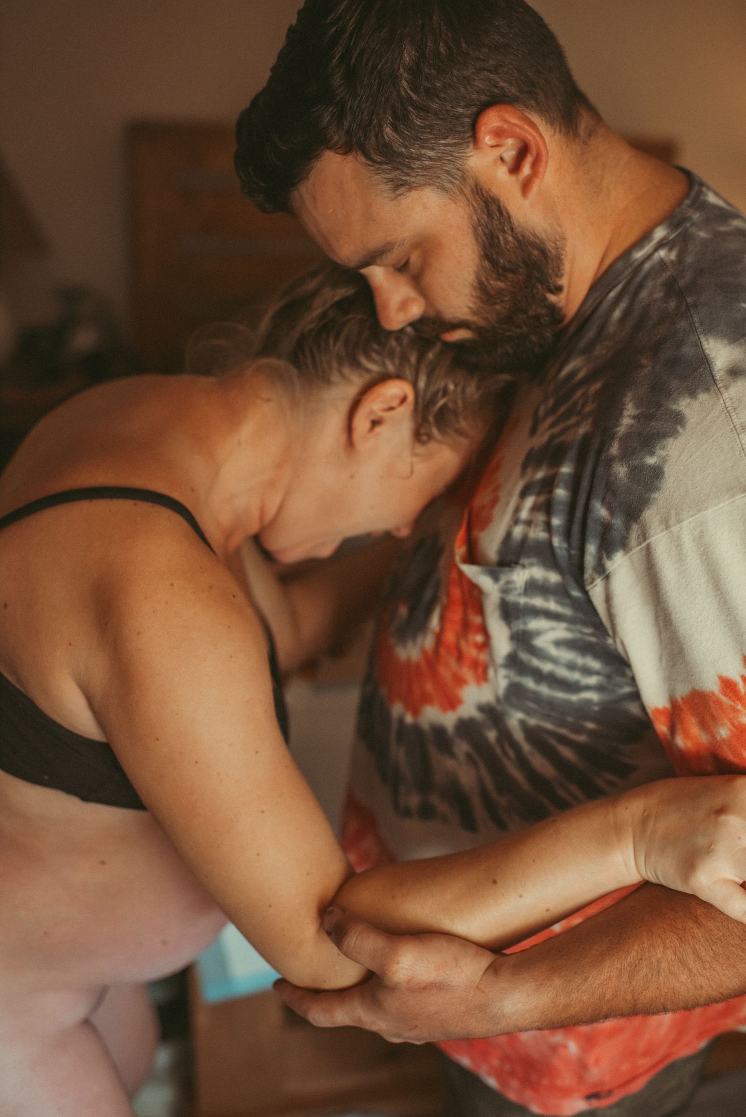 Husband holding wife while she rides a big contraction in their Suffolk, Virginia home – Virginia birth photographer