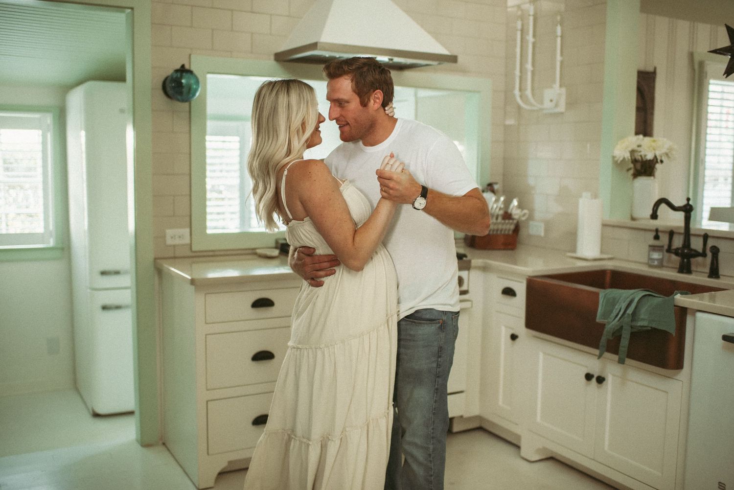 Maternity couple share a slow dance in the kitchen after baking in Virginia Beach at their maternity session.