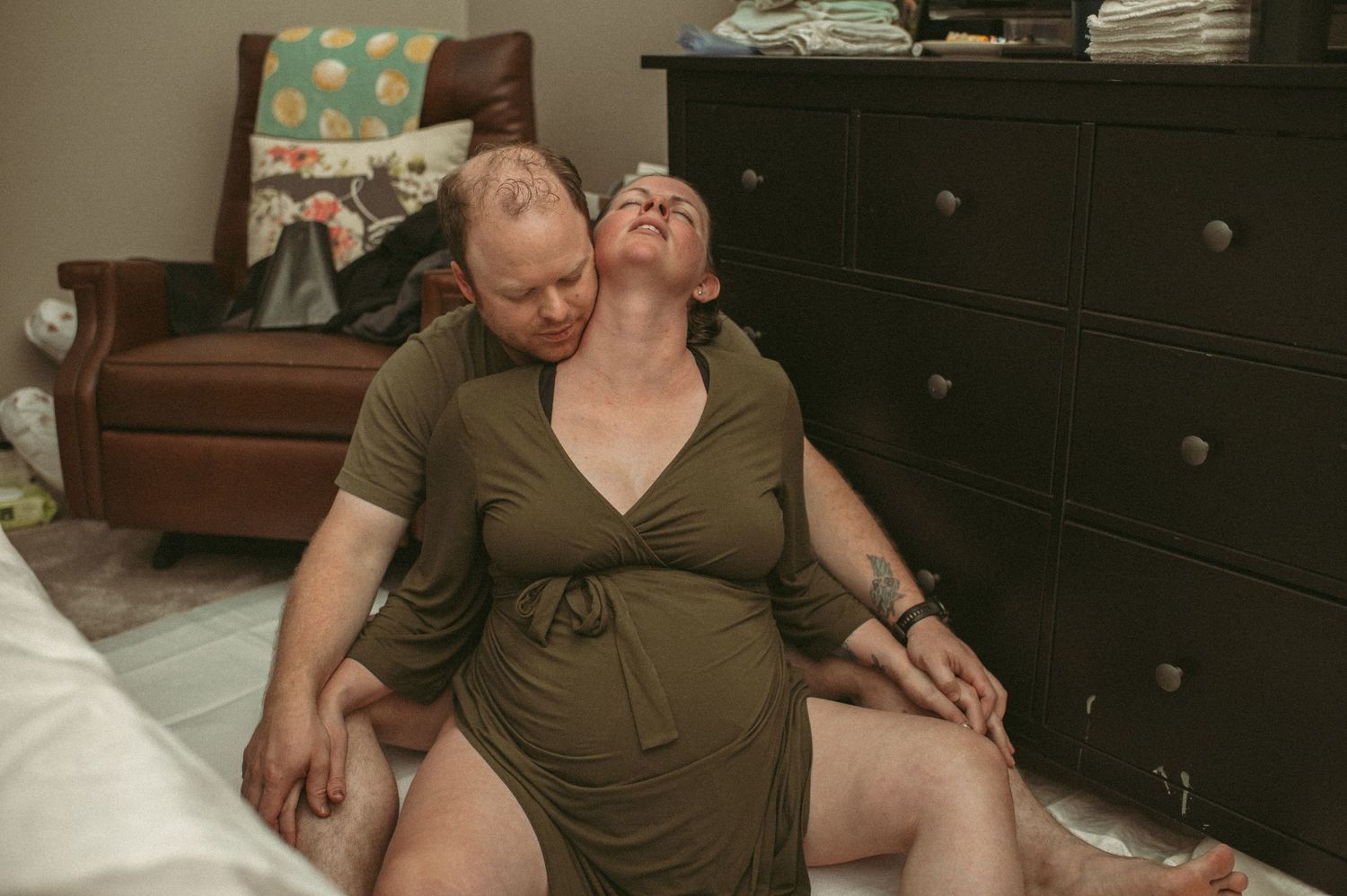 A pregnant woman leans back in comfort as her partner supports her during a home birth labor session in Chesapeake, VA.