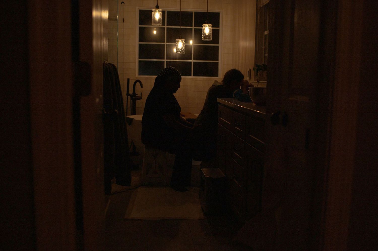 Doula and laboring mom sit in the bathroom while she labors on the toilet in her home in Hampton Roads, Virginia.