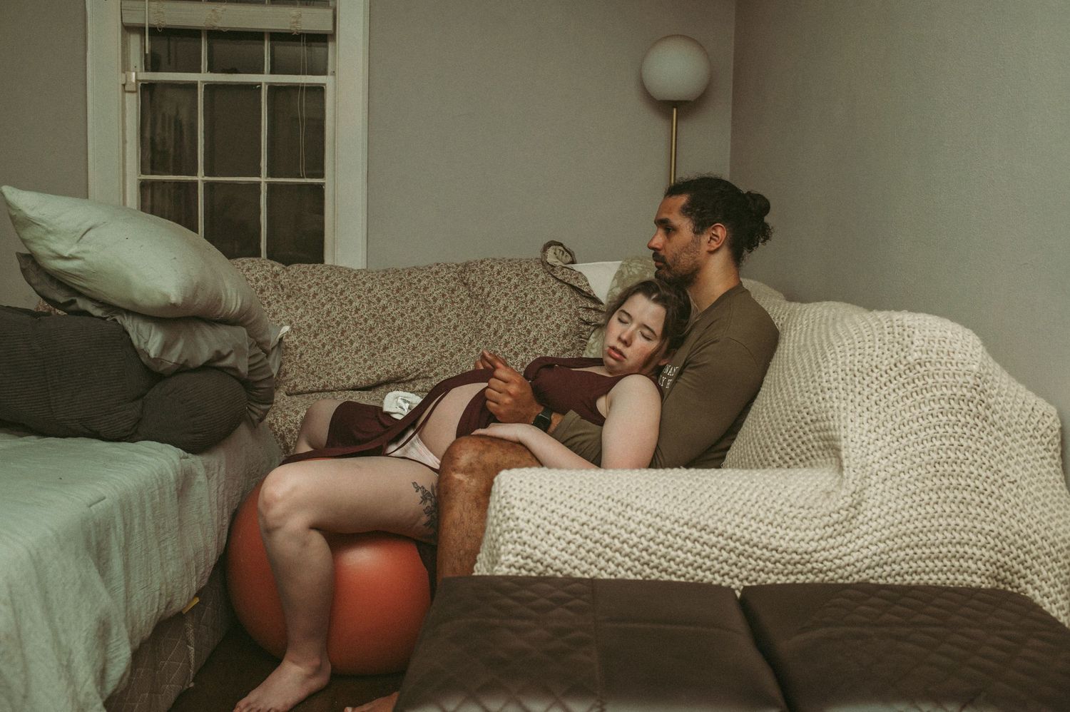 Hampton Roads husband supporting his wife through her contractions on their couch in their living room.