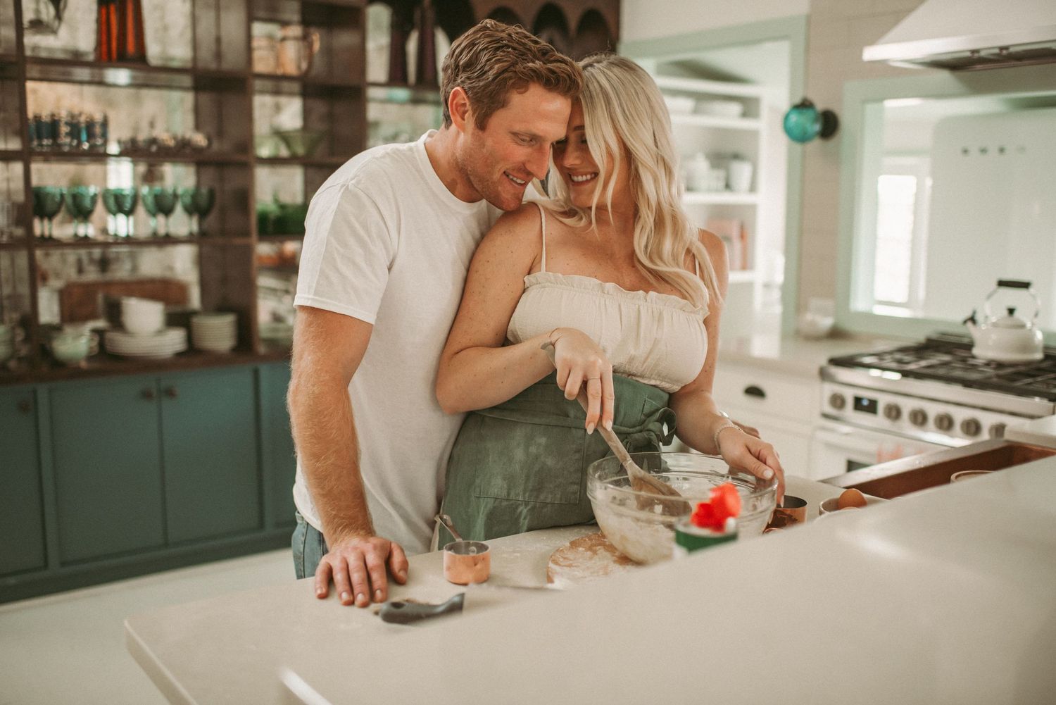 Expecting Virginia couple preparing food together in modern white kitchen with warm lighting and intimate atmosphere.