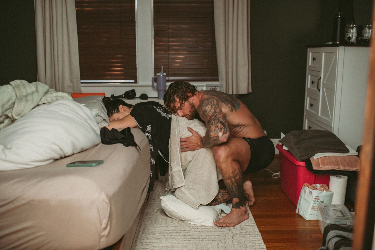Husband supports his wife during a strong contraction by squeezing her hips in their Norfolk home.
